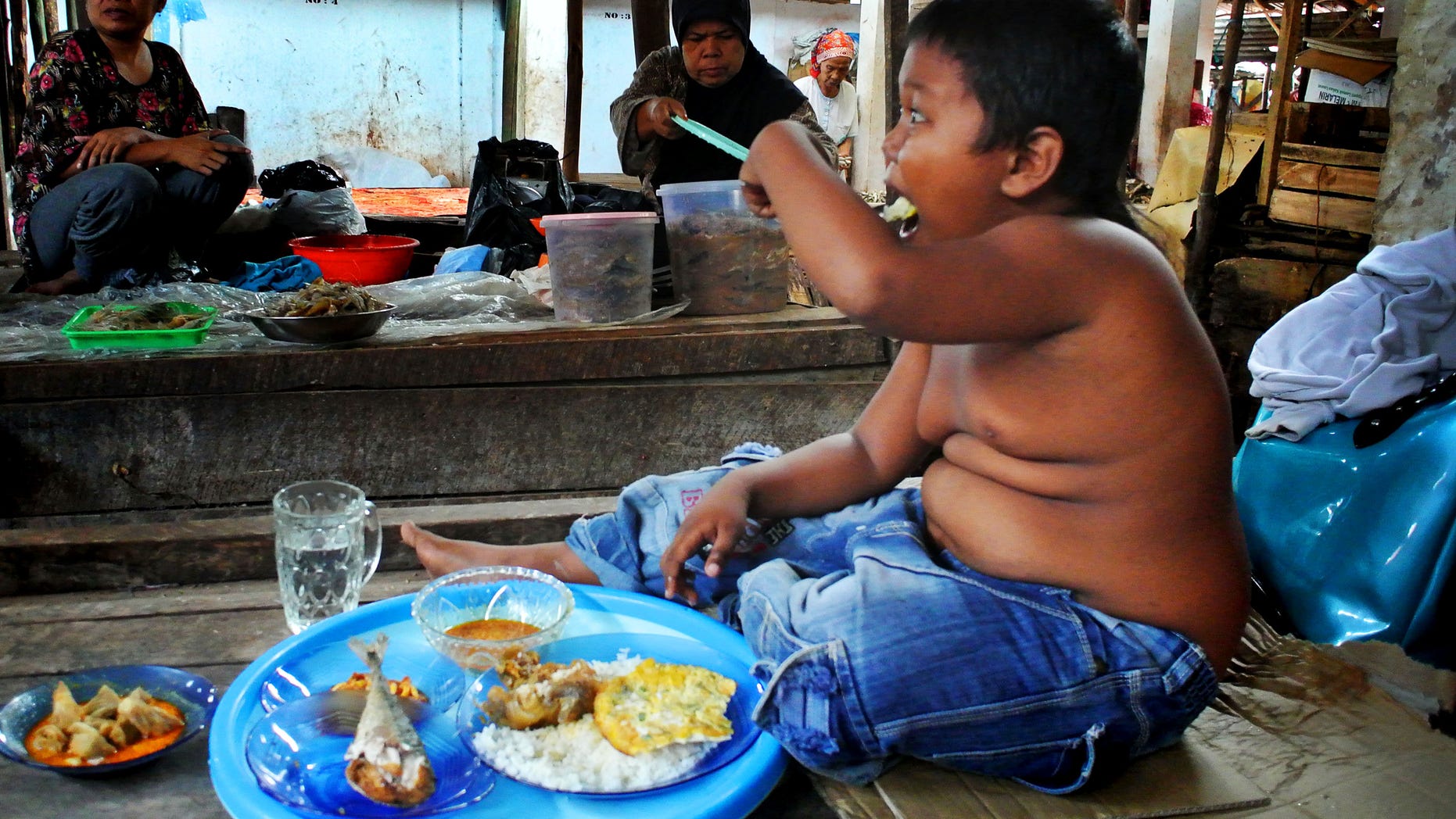 Aldi Rizal stunned the world when it was revealed he had a 40-a-day smoking habit at just 2 years old. Now at 5-years-old, the cheeky schoolboy has kicked the habit, but he's picked up a new addiction to food. His huge appetite has seen him gorge on junk food and fatty snacks - including three cans of condensed milk a day.
