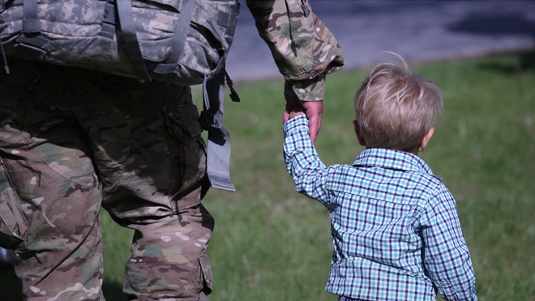 A father and son walk from a welcome-home ceremony for soldiers returning from Iraq on May 17, 2016 at Fort Drum, New York. (Photo by John Moore/Getty Images)