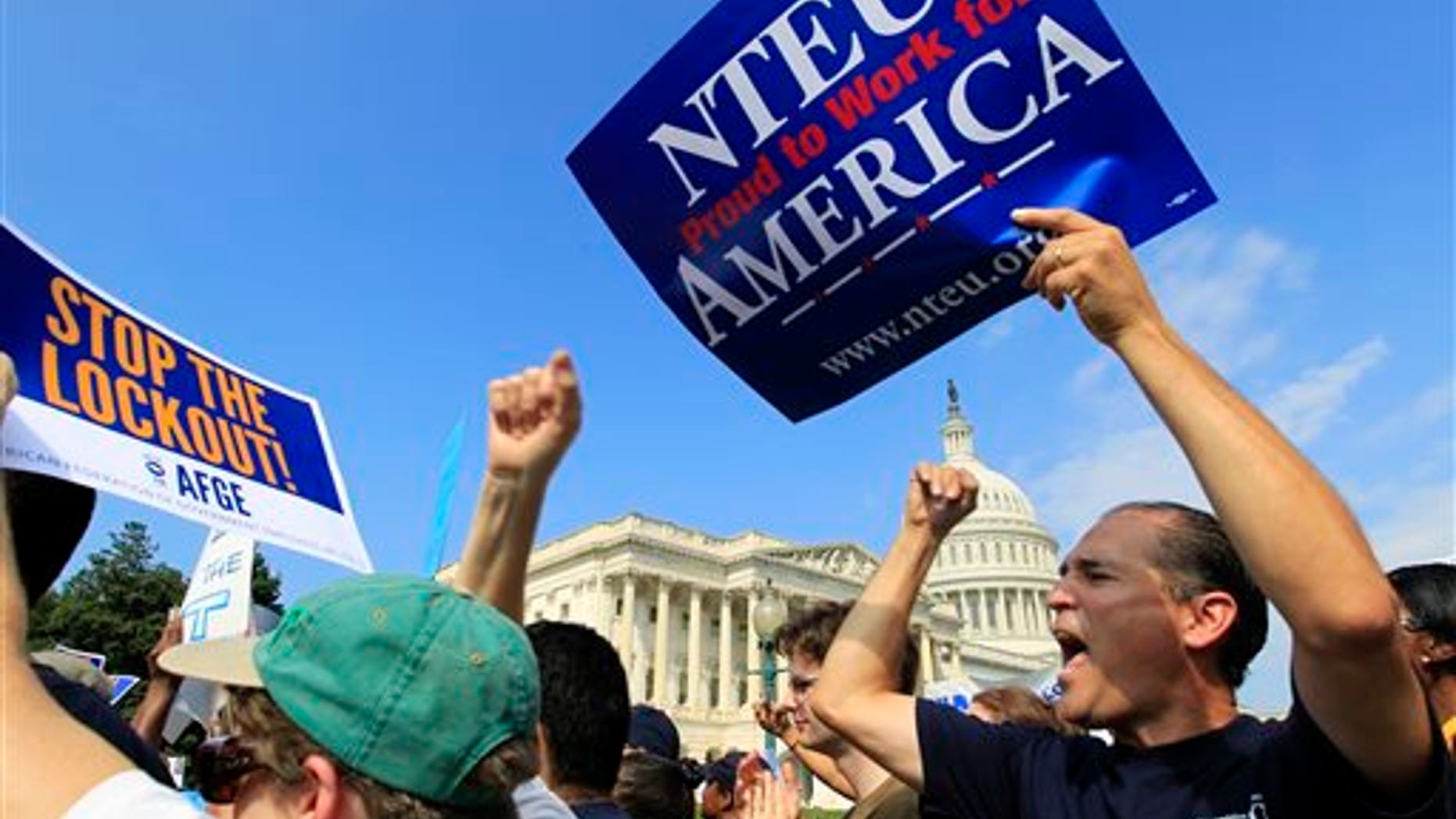 In this photo taken Friday, Oct. 4, 2013, Marcelo del Canto, right, a budget analyst for the Substance Abuse and Mental Health Services Administration, demonstrates during a rally against the government shut down during a federal union workers demonstration with congressmen outside of the U.S. Capitol in Washington. These days, many federal workers are frustrated, anxious and growing tired of being pawns in a never-ending political struggle over government funding. Both he and his federally-employed wife been furloughed and worry about making the next mortgage payment on a house they bought in March. (AP Photo/Jose Luis Magana)