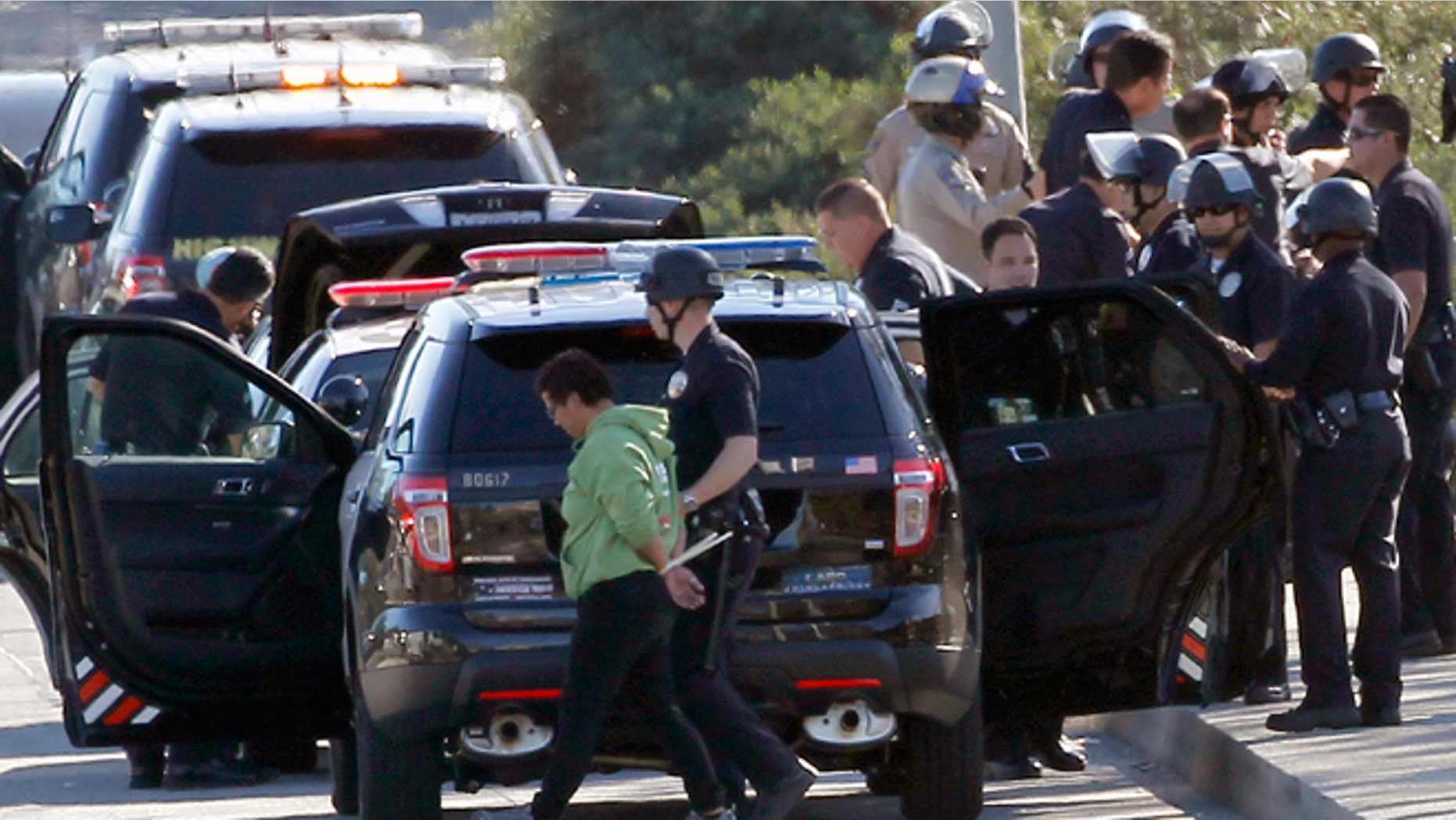 A protestor is handcuffed and taken away by a police officer after the arrest of a small group of protesters who sat down in a bus lane alongside the U.S. 101 near downtown Los Angeles on Wednesday, Nov. 26, 2014. Since a grand jury's decision was announced Monday night, Nov. 24, not to indict a white Ferguson, Mo., police officer who killed Michael Brown, an unarmed black teen, protesters in cities throughout the country have rallied behind the refrain "hands up, don't shoot," and drawn attention to other police killings. Los Angeles Police Chief Charlie Beck says a total of nine people were arrested at the midmorning protest. (AP Photo/Nick Ut)