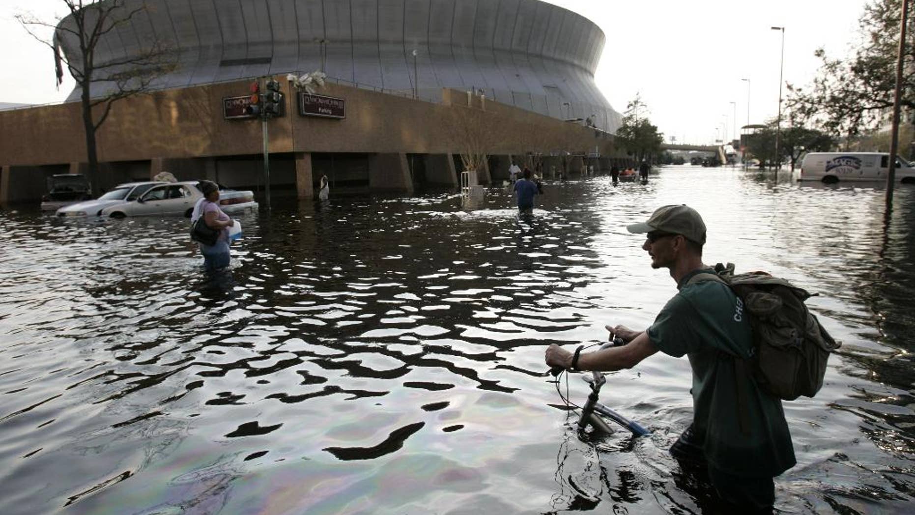 FILE - This Aug, 31, 2005 file photo shows a man pushing his bicycle through flood waters near the Superdome in New Orleans after Hurricane Katrina left much of the city under water. A new but controversial study asks if an end is coming to the busy Atlantic hurricane seasons of recent decades. The Atlantic looks like it is entering in to a new quieter cycle of storm activity, like in the 1970s and 1980s, two prominent hurricane researchers wrote Monday in the journal Nature Geoscience.(AP Photo/Eric Gay, File)