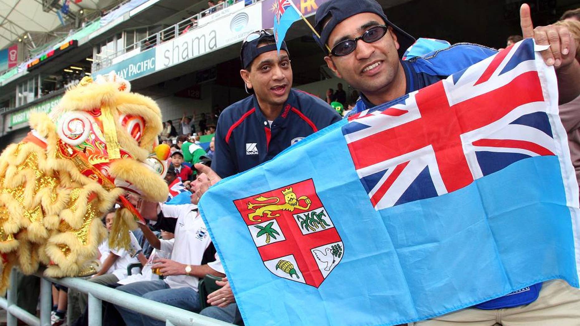FILE - In this Friday, March 18, 2005, file photo, rugby fans hold a Fiji national flag during the Rugby World Cup Sevens in Hong Kong. Fiji Prime Minister Voreqe Bainimarama announced Friday, Feb. 27, 2015, the Pacific island nation is launching a two-month competition to find the best design for a new flag. (AP Photo/Water Chan, File)