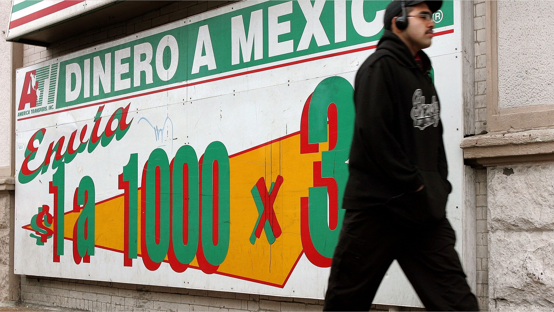 A man walks past an a sign outside a a Mexican currency exchange November 29, 2005 in Chicago, Illinois. Hispanics have become a growing force in the U.S economy and politics. (Photo by Tim Boyle/Getty Images)