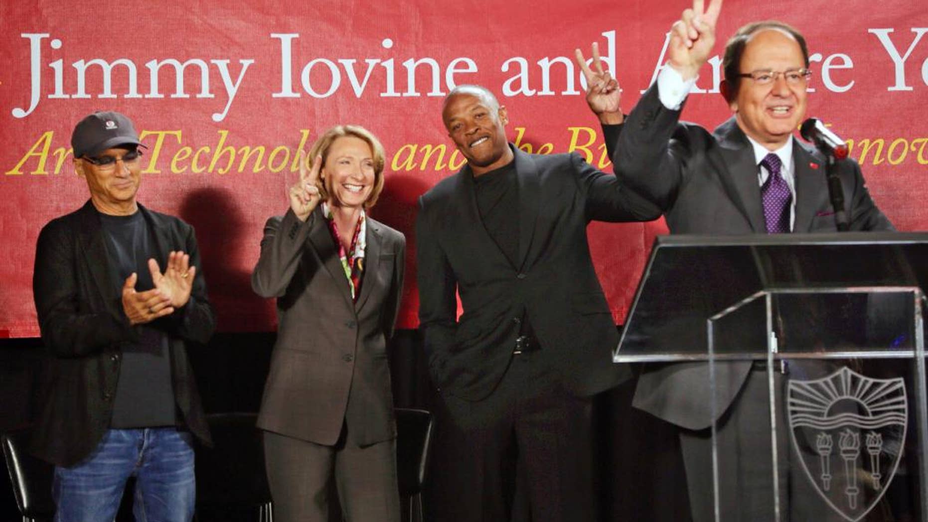 FILE - In this May 15, 2013 file photo, University of Southern California President C.L. Max Nikias, right, appears with, from left, Jimmy Iovine, the co-founder of Interscope Records, Erica Muhl, dean of the USC Roski School of Fine Arts, and hip-hop mogul Andre "Dr. Dre" Young as they announce a $70 million dollar donation to create the Jimmy Iovine and Andre Young Academy for Arts and Technology and Business Innovation at USC, during a news conference in Santa Monica, Calif. The entire graduate class of 2016 of what is now known as the USC Roski School of Art and Design has dropped out, protesting faculty and curriculum changes. The seven fine arts students on Friday, May 15, 2015 posted a letter online, saying they're withdrawing from the school because of changes to the visual arts graduate program after they enrolled and the loss of several prominent professors, according to the Los Angeles Times.(AP Photo/Damian Dovarganes, File)