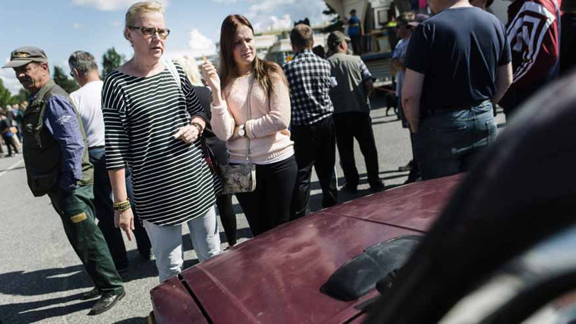 Kristiina Lappalainen and daughter Malla view one of the cars on auction during an auction as Asylum seekers' abandoned cars in Salla, northern Finland, on Friday July 15, 2016. Over 100 old cars, mostly Russian-made, driven across the northeastern Finnish border by asylum seekers and abandoned at the Salla border crossing point this past winter are auctioned in a two-day event in Salla. (Jouni Porsanger/Lehtikuva via AP) FINLAND OUT - NO SALES