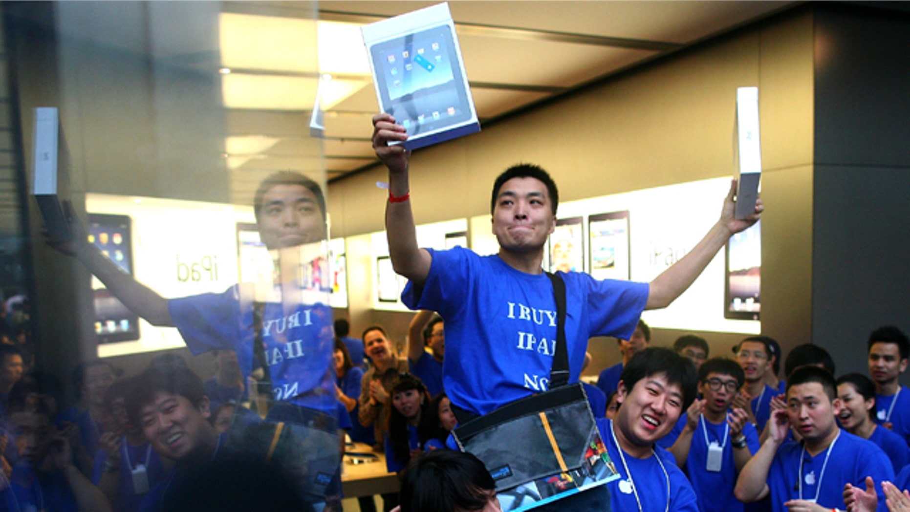 Han Ziwen holds up his iPads while being carried out by store employees at the Apple flagship store in Beijing, China, Friday, Sept. 17, 2010. Han was one of the first customers to officially buy an iPad in mainland China after lining up for more than 60 hours.