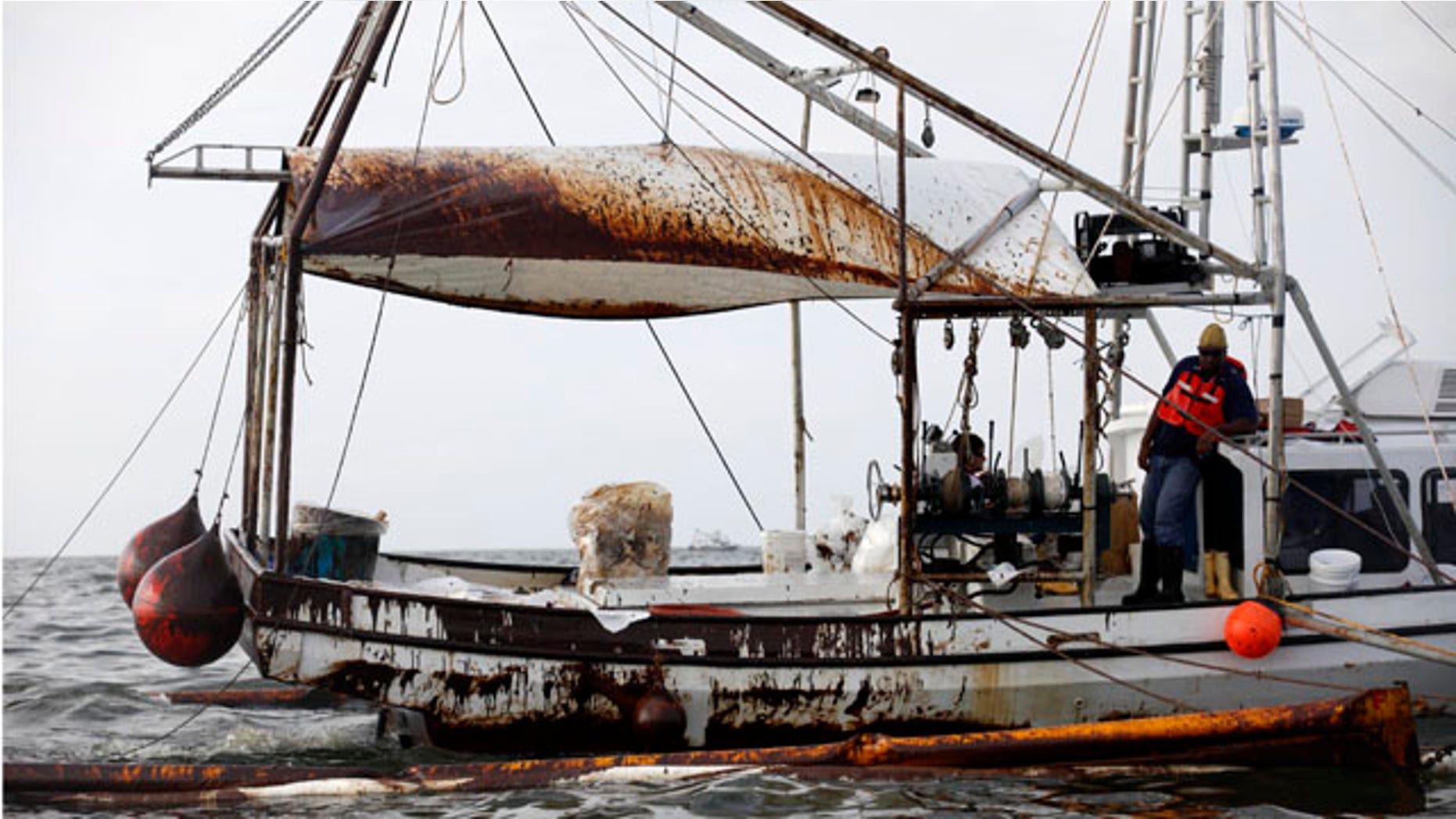 June 4: A fishing trawler covered in oil pulls oil covered booms through Barataria Bay just inland from the Gulf of Mexico in Plaquemines Parish, La