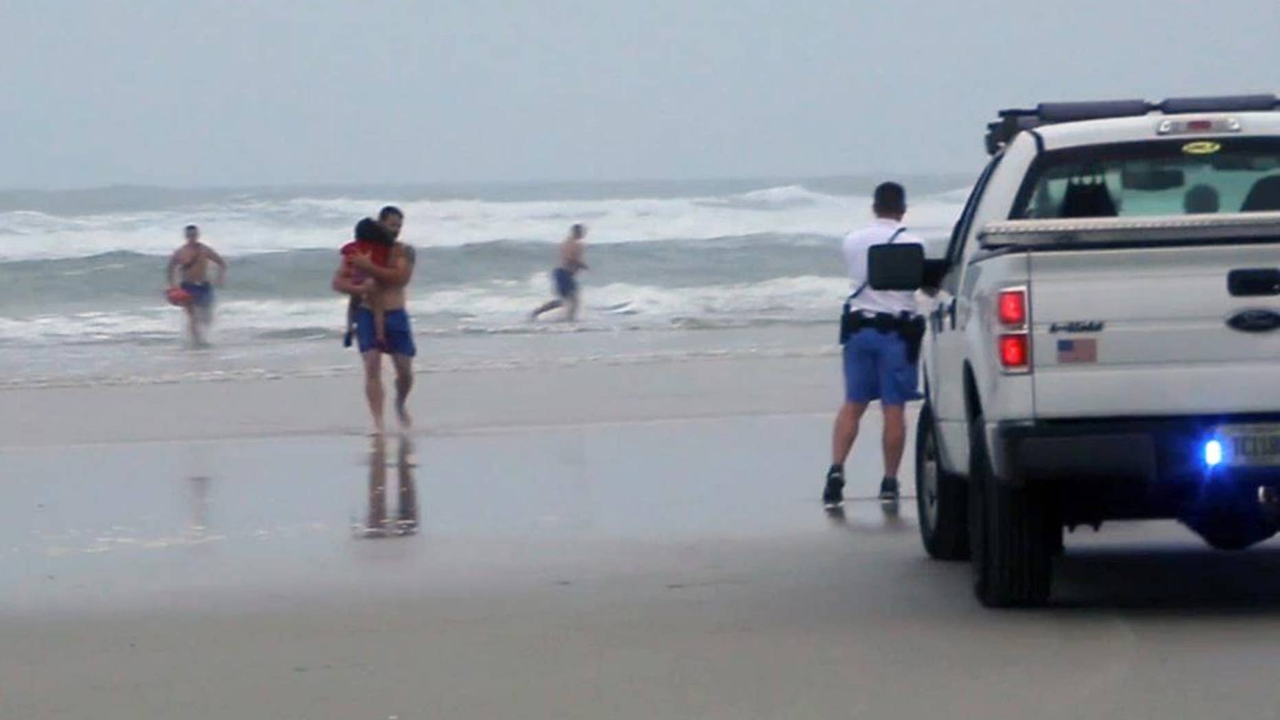 FILE - In this March 4, 2014 file image made from video, a lifeguard carries one of the three children rescued from a minivan that their mother, Ebony Wilkerson, drove into the Atlantic in Daytona Beach, Fla. Wilkerson as charged Friday with attempted first-degree murder and aggravated child abuse, though she has denied trying to harm anyone, authorities said. (AP Photo/Simon Besner, File) NO SALES