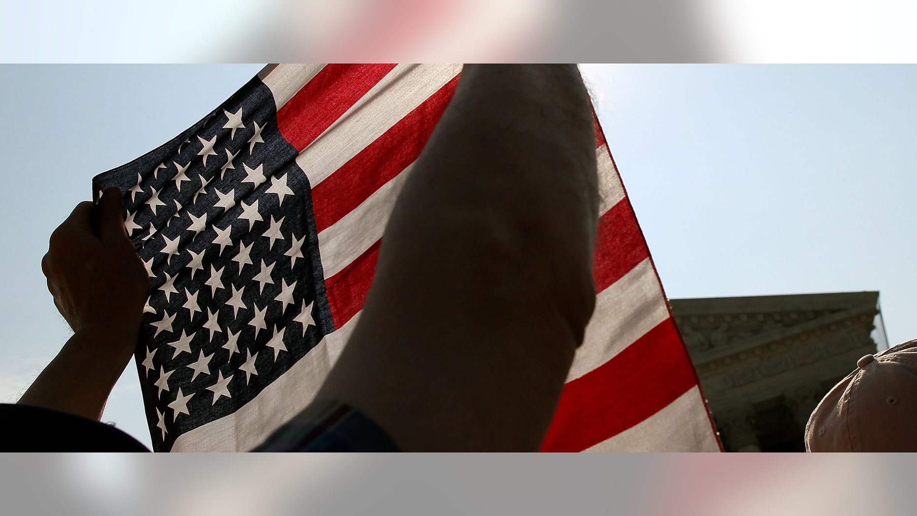WASHINGTON, DC - JUNE 28: A protester holds an American flag during a demonstration in front of the U.S. Supreme Court, on June 28, 2012 in Washington, DC. Today the high court is expected to rule on the constitutionality of the sweeping health care law championed by President Barack Obama. (Photo by Mark Wilson/Getty Images)