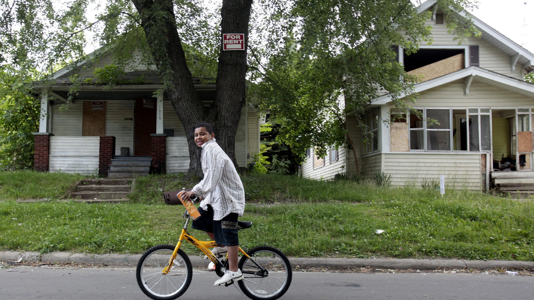July 8, 2009 - FILE photo of a boy riding his bike past several abandoned houses in a former thriving working-class neighborhood that is now littered with blight in Flint, Michigan. A home in Flint recently went on the market for a mere $188.