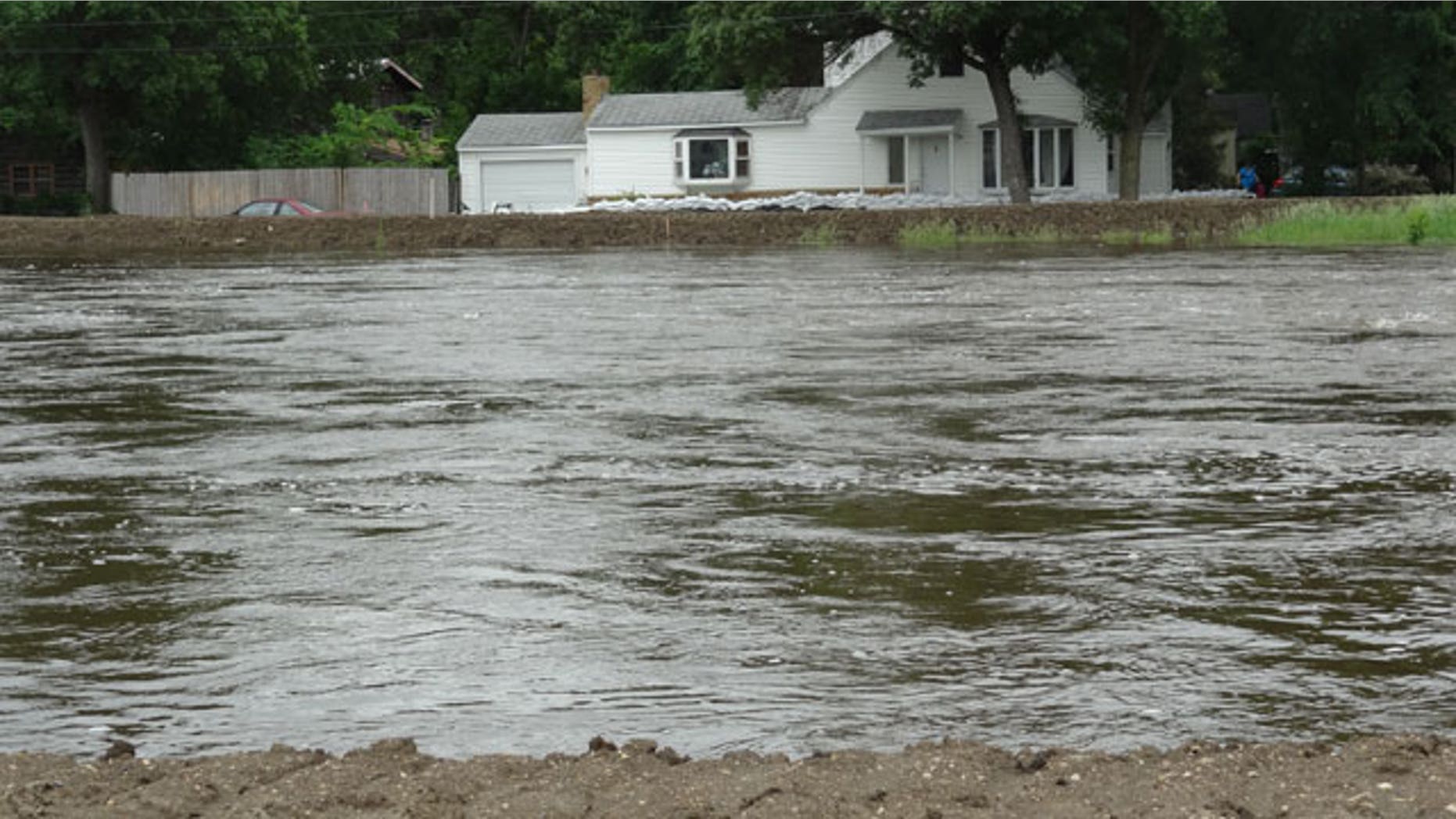 The Souris River passes near a home Tuesday, June 21, 2011, in Minot, N.D. About 11,000 Minot residents are being ordered to leave their homes even earlier than expected this week as the river gets closer to swamping the North Dakota city with the worst flooding in four decades, officials said Tuesday.
