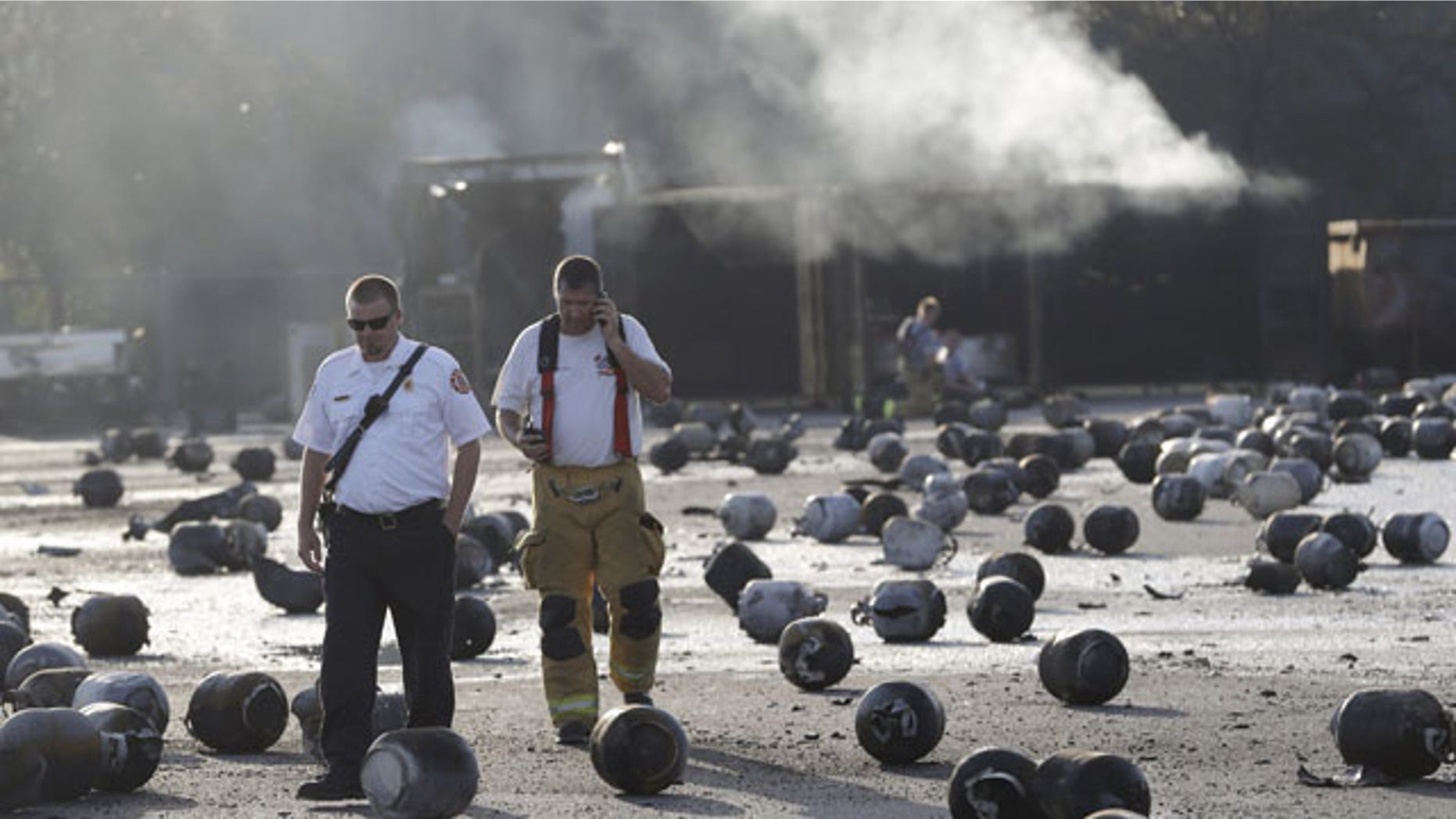 July 30, 2013: Firefighters walk through an area of exploded propane cylinders in the aftermath of an explosion and fire at a propane gas company in Tavares, Fla. (AP Photo)