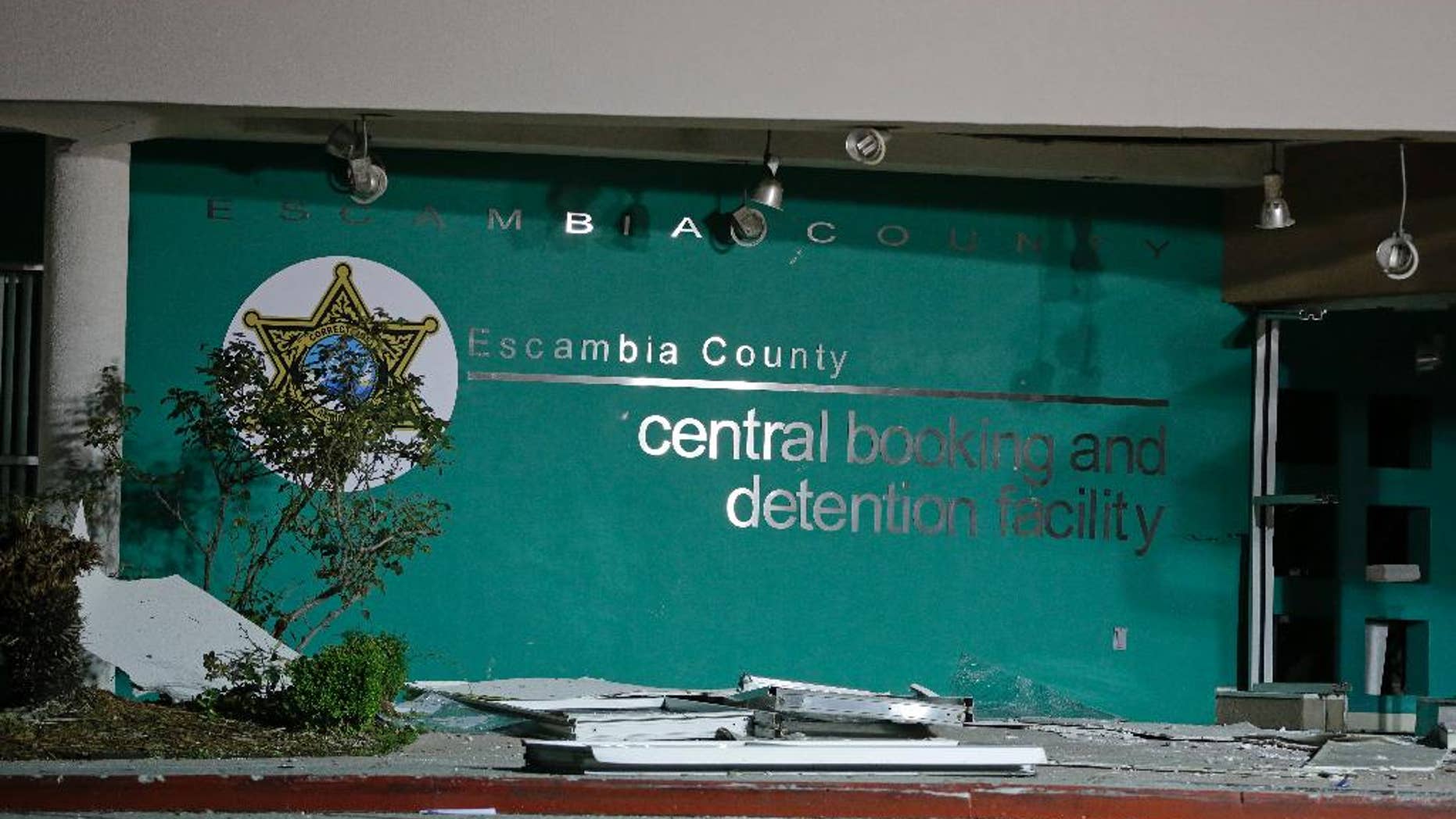 FILE - In this file photo from May 1, 2014, debris is scattered on the sidewalk in front of the Escambia County Jail after an explosion forced the evacuation of the facility in Pensacola, Florida. A report released Thursday by the State Attorney’s Office said a grand jury concluded that there wasn’t enough evidence to bring criminal charges. The explosion killed two inmates and left a guard paralyzed after it ripped through the jail's bottom floor. (AP Photo/John Raoux, File)