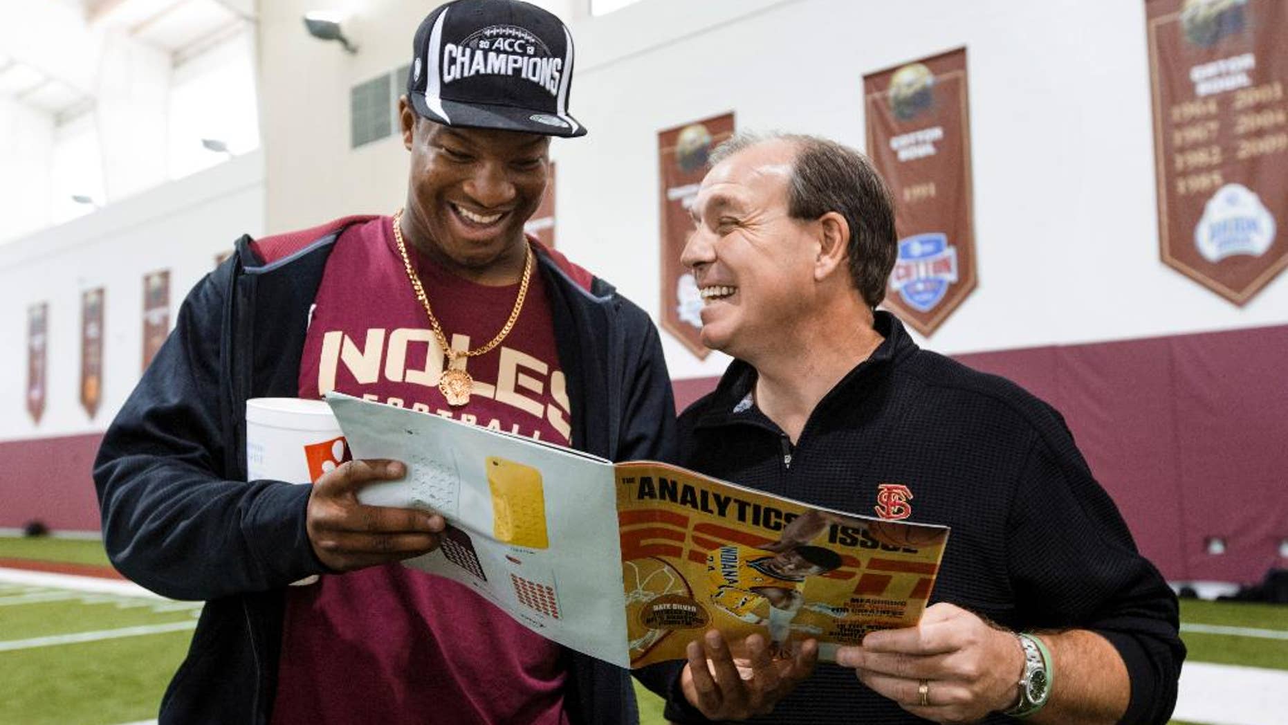 Florida State Jimbo Fisher, right, looks at a magazine with quarterback Jameis Winston during pro day at Florida State on Tuesday, March 18, 2014, in Tallahassee, Fla. Winston did not participate in pro day, but came by to visit Fisher after the event. (AP Photo/Colin Hackley)