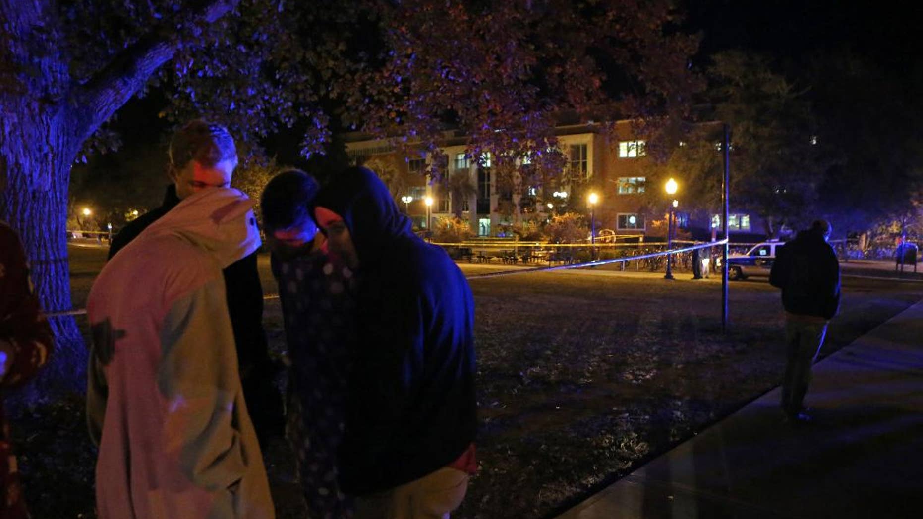 A group of students call their friends still locked down in Strozier Library, background, after a shooting on Thursday, Nov. 20, 2014, in Tallahassee, Fla. (AP Photo/Steve Cannon)