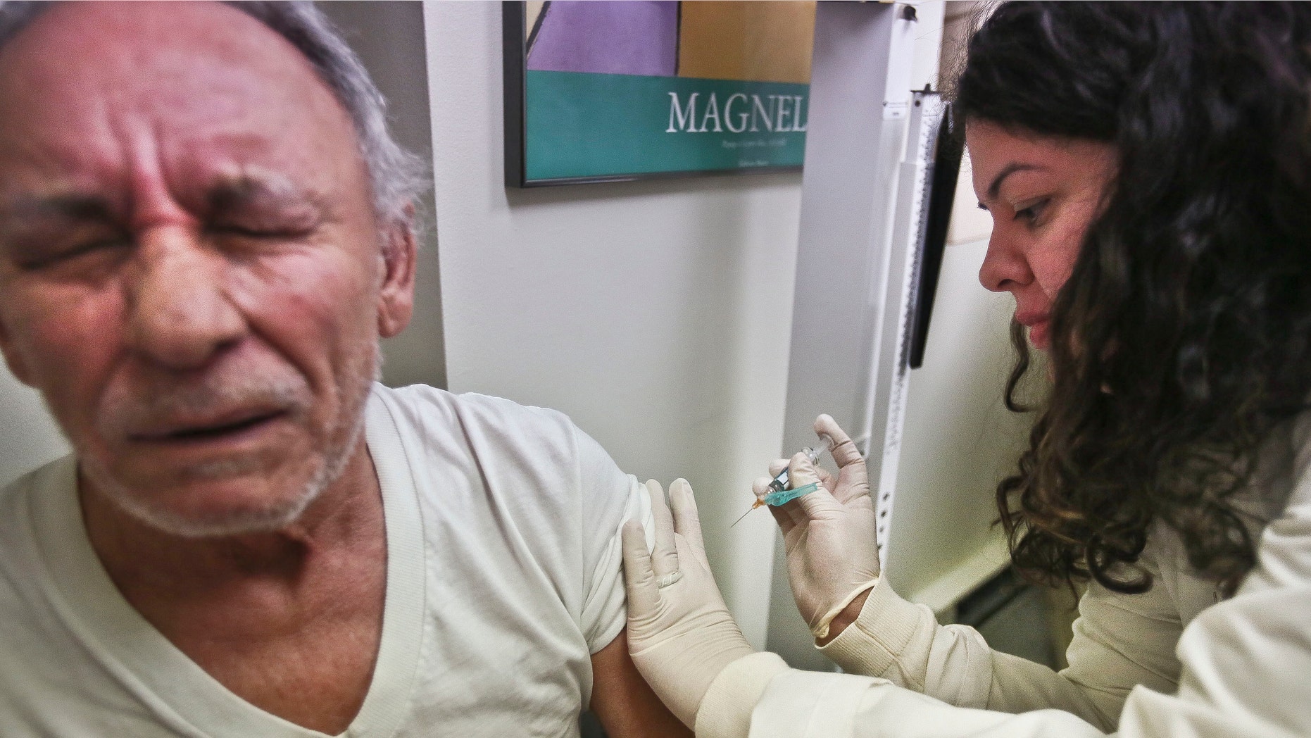 FILE -Carlos Maisonet, 73, reacts as Dr. Eva Berrios-Colon, a professor at Touro College of Pharmacy, injects him with flu vaccine during a visit to the faculty practice center at Brooklyn Hospital in New York.