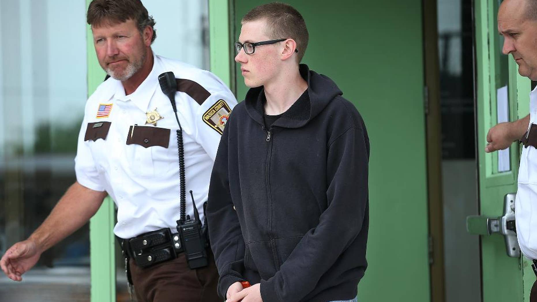 In this photo taken June 30, 2014, John LaDue, accused of planning an attack on his school, is escorted by Waseca County Sheriff's Deputies for a hearing in Waseca, Minn. District Judge Robert Birnbaum on Friday, Aug. 21, 2015, has certified the Waseca teenager, accused of planning to kill his family and attack his high school, to stand trial as an adult. (Elizabeth Flores/Star Tribune via AP) MANDATORY CREDIT; ST. PAUL PIONEER PRESS OUT; MAGS OUT; TWIN CITIES LOCAL TELEVISION OUT