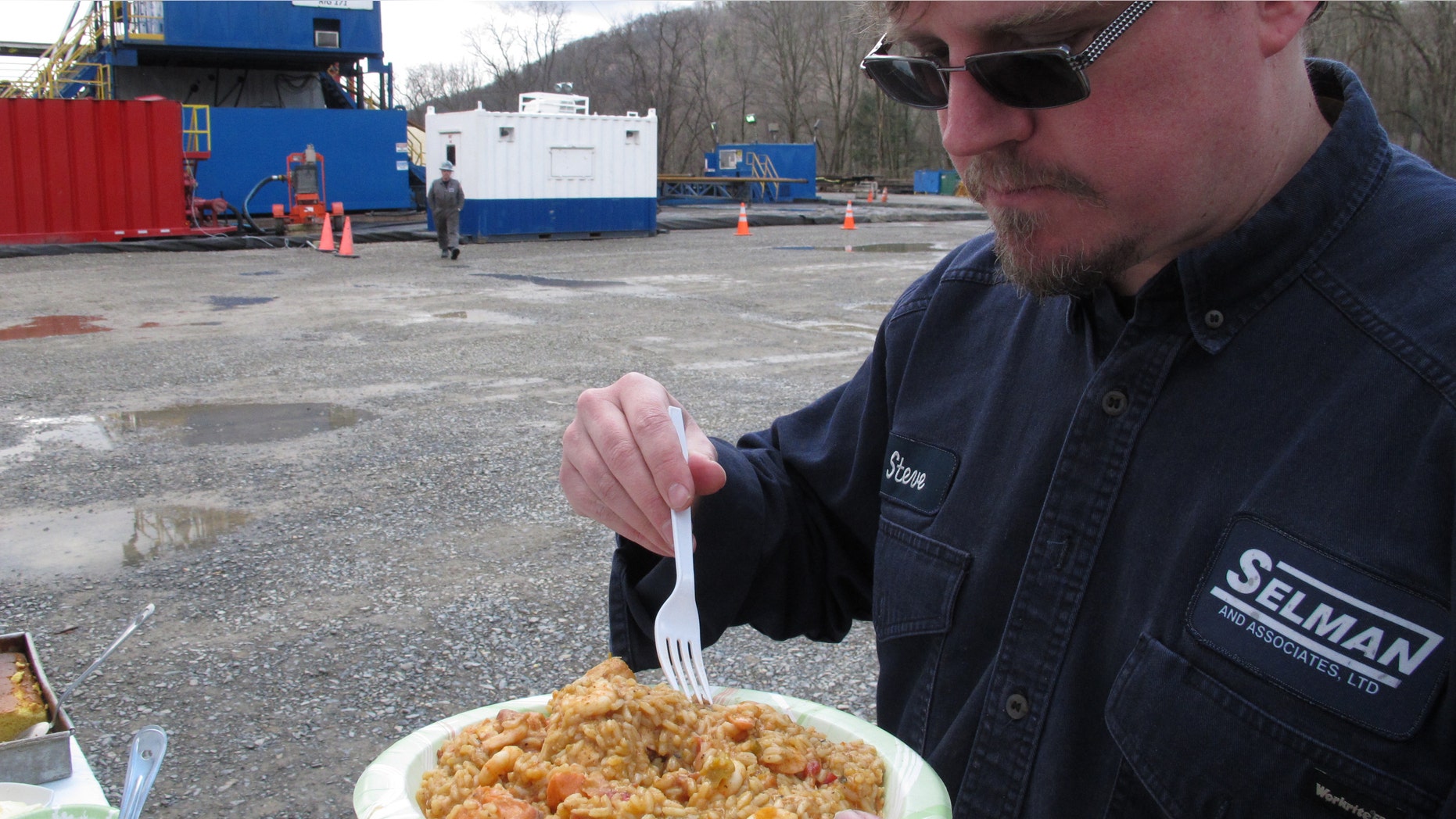 Geologist Steve Clark prepares to take a bite of jambalaya prepared for workers on a natural gas drilling site near Montoursville, Pa.