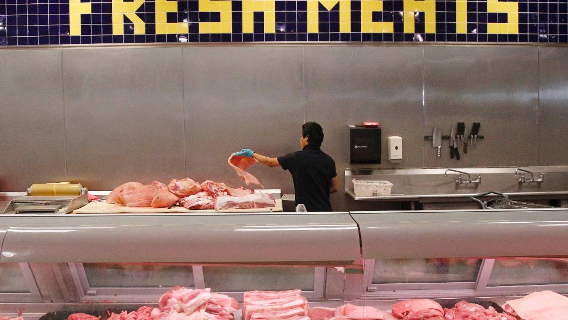 FILE - In this July 25, 2012 file photo butcher Freddie Quina cuts meat at Super Cao Nguyen in Oklahoma City. The highest beef prices in decades _ fresh beef climbing to $5.28 a pound in February 2014, up from $5.04 in January _ have some consumers spending extra time in meat market aisles as they search for cuts that won’t break their budgets. (AP Photo/Sue Ogrocki)