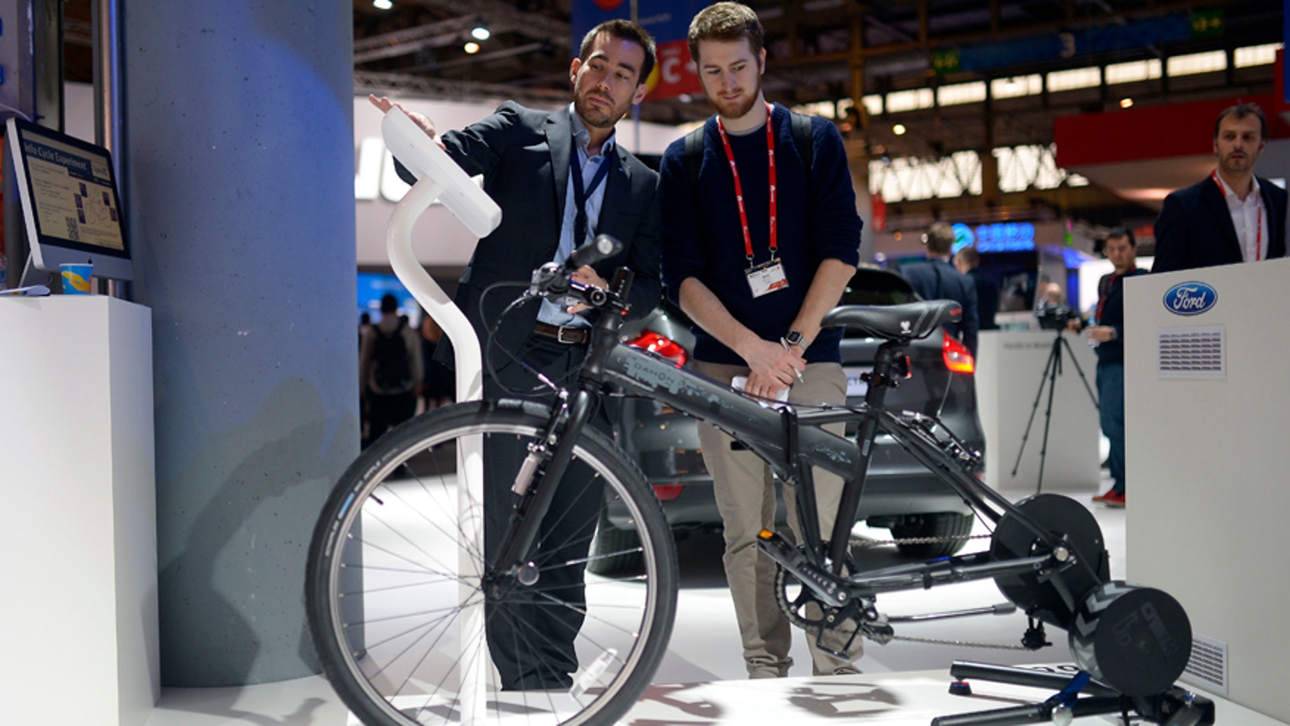 A worker shows a visitor the e-bike from Ford at the Mobile World Congress.