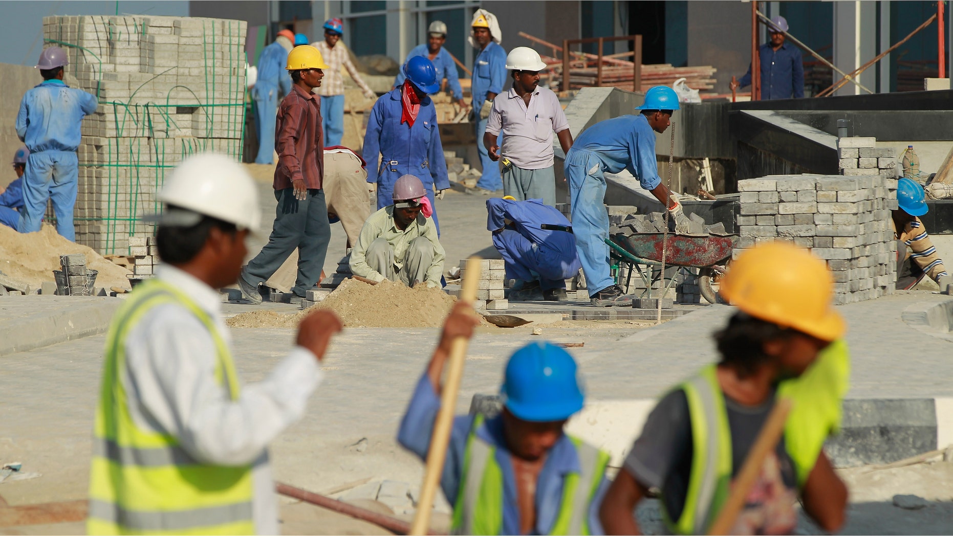 DOHA, QATAR - OCTOBER 24: Foreign workers lay an entrance road at the construction site of a new hotel in the new City Center and West Bay district on October 24, 2010 in Doha, Qatar. The International Monetary Fund (IMF) recently reiterated its projection for the Qatari economy with predictions of double digit growth for 2010 and 2011. Though natural gas and petroleum production are still the biggest two single sources of income, the non-energy sector overtook oil and gas in Qatari GDP for 2009. Qatar is heavily dependant on foreign labour from countries such as India, Sri Lanka, Bangladesh, the Phillipines and other Arab countries. Foreigners make up approximately two thirds of the Qatari population. (Photo by Sean Gallup/Getty Images)