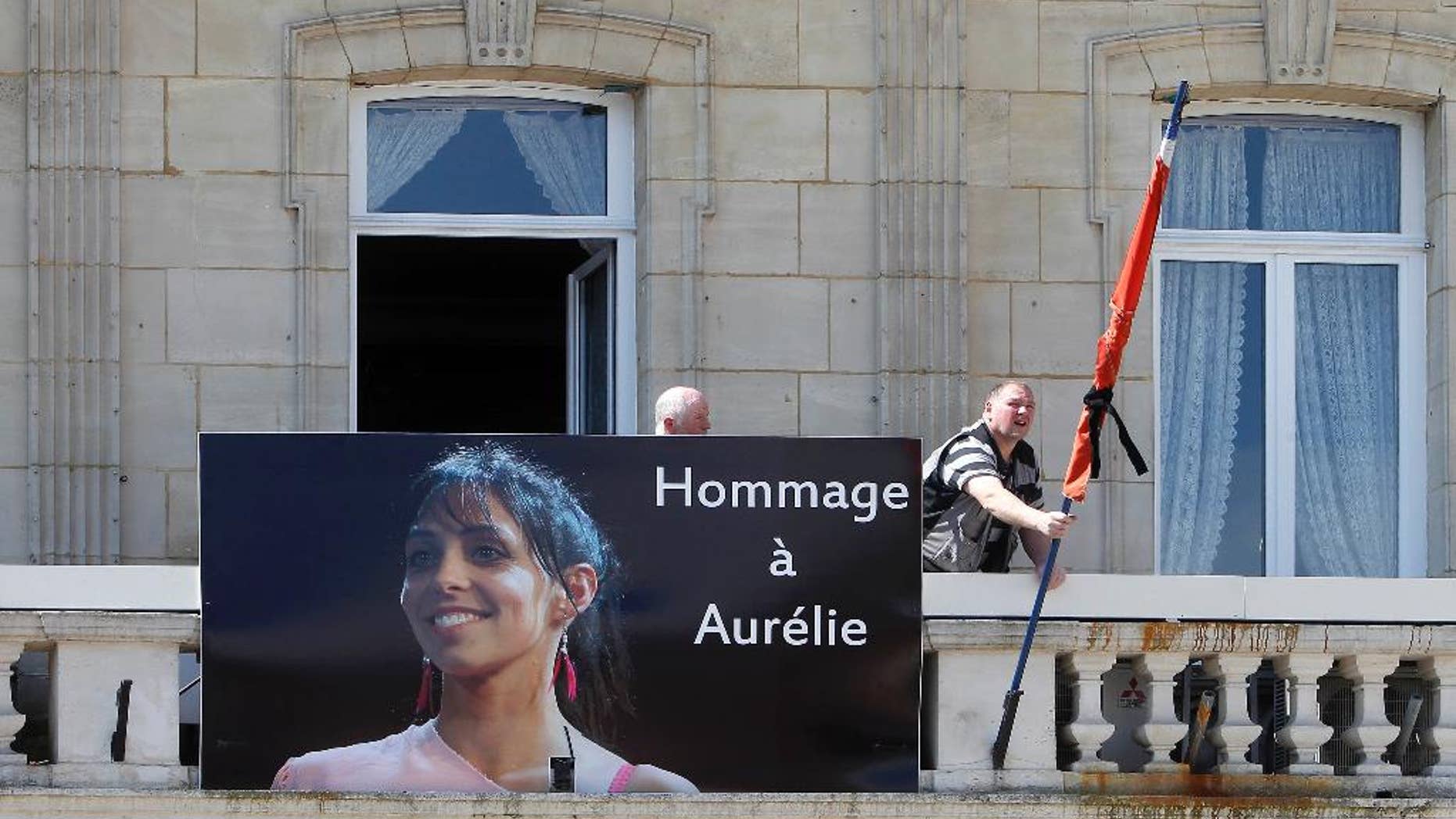 Workers hang a banner showing a portrait of Aurelie Chatelain while a black ribbon is set up around the French flag on the front of the city hall of Caudry, northern France, Wednesday, April 22, 2015. An Islamic extremist with an arsenal of loaded guns was only prevented from opening fire on churchgoers because he accidentally shot himself in the leg, French officials said Wednesday. Aurelie Chatelain, a 32-year-old Frenchwoman visiting Paris for a training session for her work, was found shot to death on Sunday morning in her car. The security official said Chatelain appeared to have been killed at random and ballistics evidence linked her death to the suspect.( AP Photo/Michel Spingler)