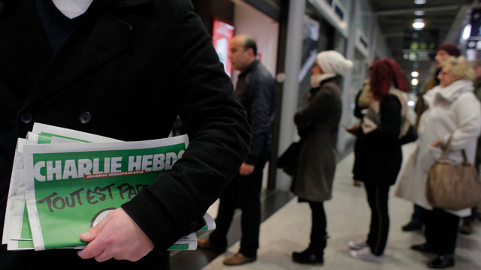 Jan. 14, 2015: A man leaves after buying Charlie Hebdo newspapers as people queue at a newsstand in Paris. (AP Photo/Christophe Ena)