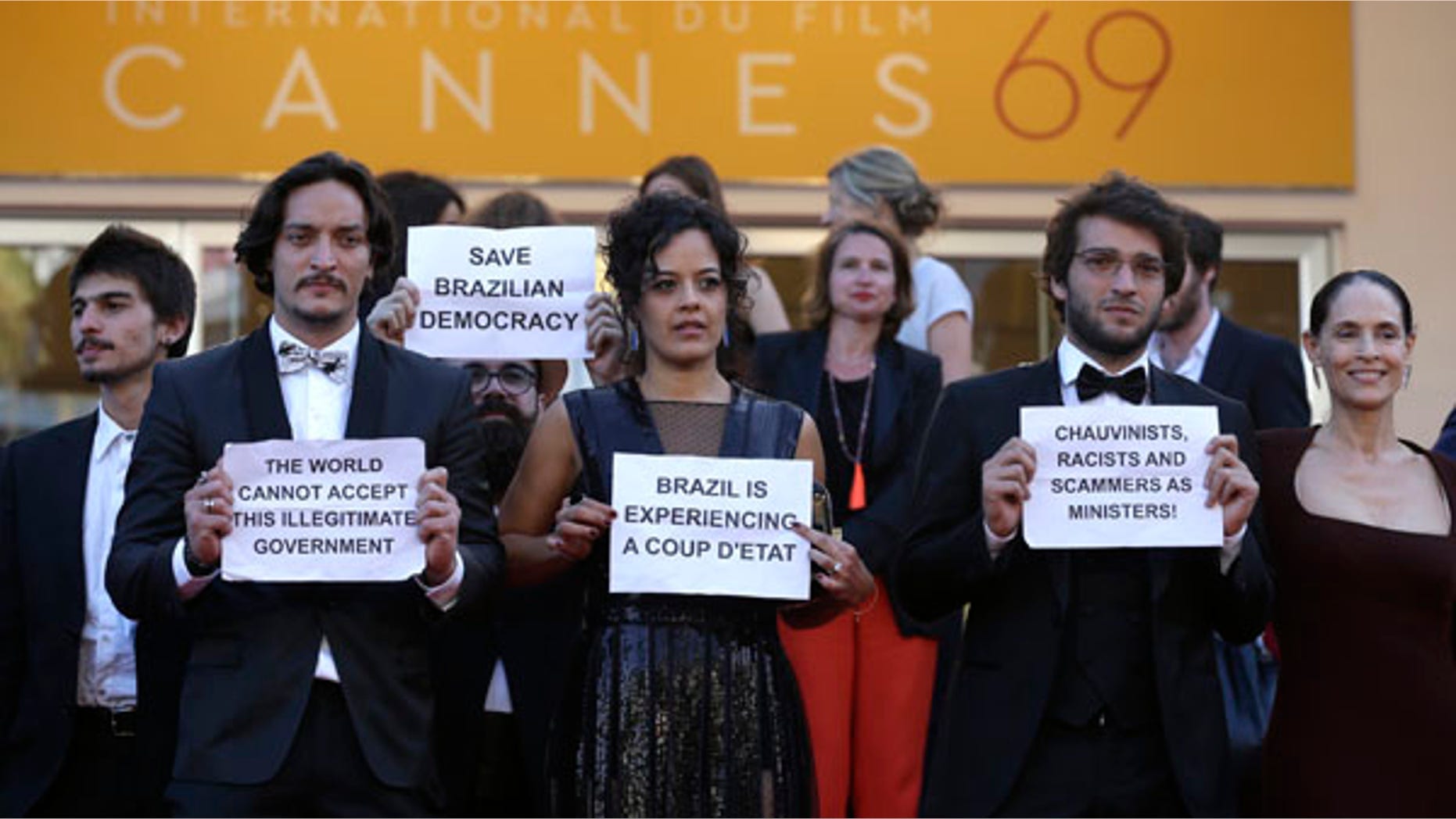 Cast from the Brazilian film Aquarius hold placards protesting against the current political landscape in Brazil after departing the screening of the film at the 69th international film festival, Cannes, southern France, Tuesday, May 17, 2016. (AP Photo/Lionel Cironneau)