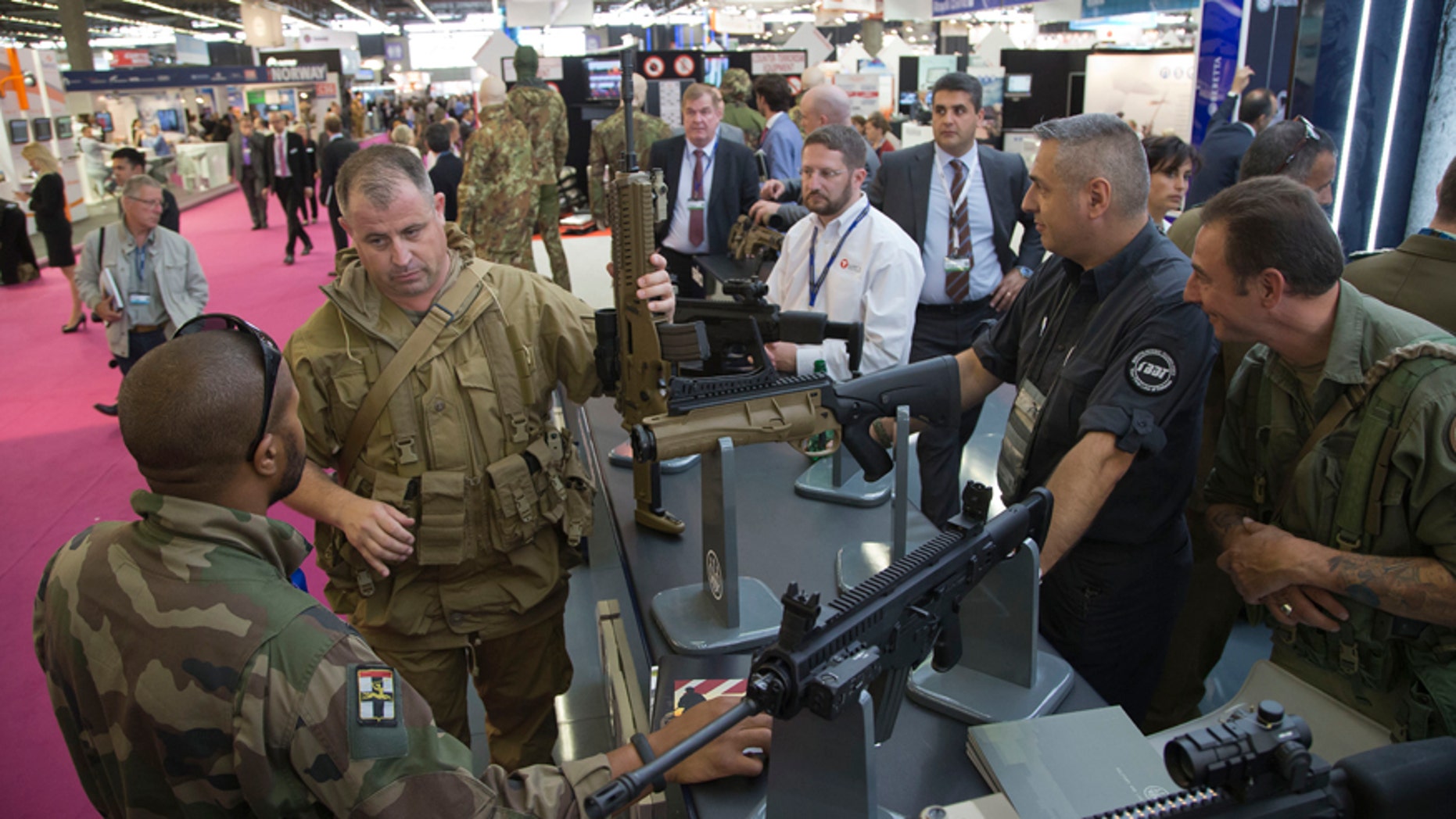 A member of the French army, left, looks at a assault rifle manufactured by US company Beretta, presented at the Eurosatory Defence and Security trade show, in Villepinte, outside Paris, Monday, June 16, 2014. Over 1500 exhibitors will take part in the trade show which takes place in the north of Paris from June 16 to June 20.