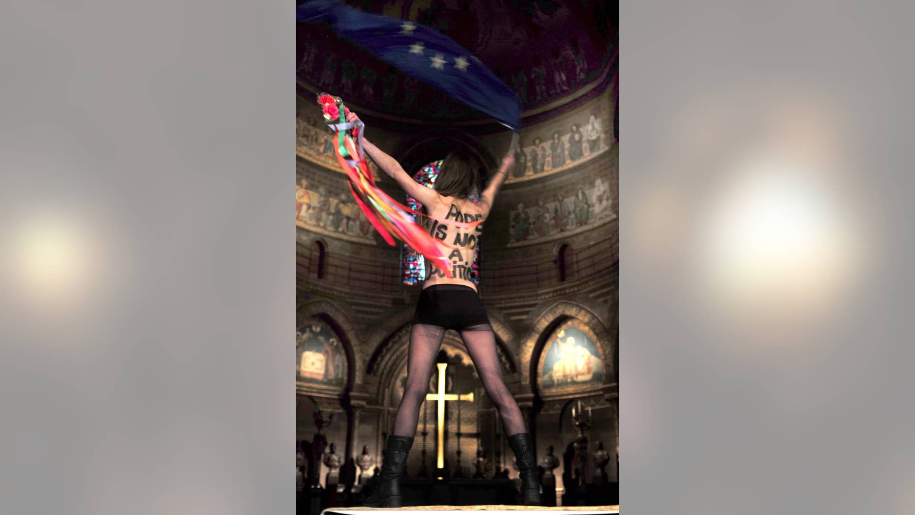 A member of the Ukrainian feminist protest group FEMEN, waves the European Union flag, as she stages a protest inside the cathedral of Strasbourg, eastern France, Monday, Nov. 24, 2014 against Tuesday's visit of the Pope to Strasbourg . Pope Francis is set to deliver his first major speech on Europe with a holistic, if not holy, look at complex continental issues like joblessness and immigration. The pontiff's whirlwind, 4-hour visit Tuesday to the European Parliament and the Council of Europe, Europe's main human rights body, in Strasbourg is shaping up as more a secular stop than a liturgical layover. (AP/Photo Christian Lutz)