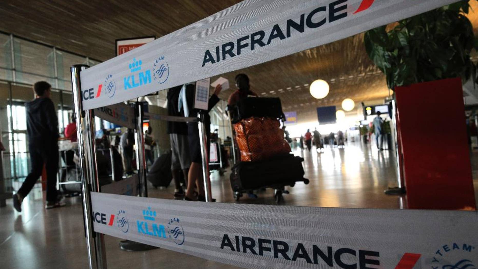 Travellers walk past an Air France desk at Paris Charles de Gaulle airport, in Roissy, near Paris, Wednesday, Sept. 17, 2014. Air France canceled at least half its flights around the world on Monday as pilots began a weeklong strike, highlighting the trouble Europe's flagship airlines face in keeping up with low-cost competitors. (AP Photo/Christophe Ena)