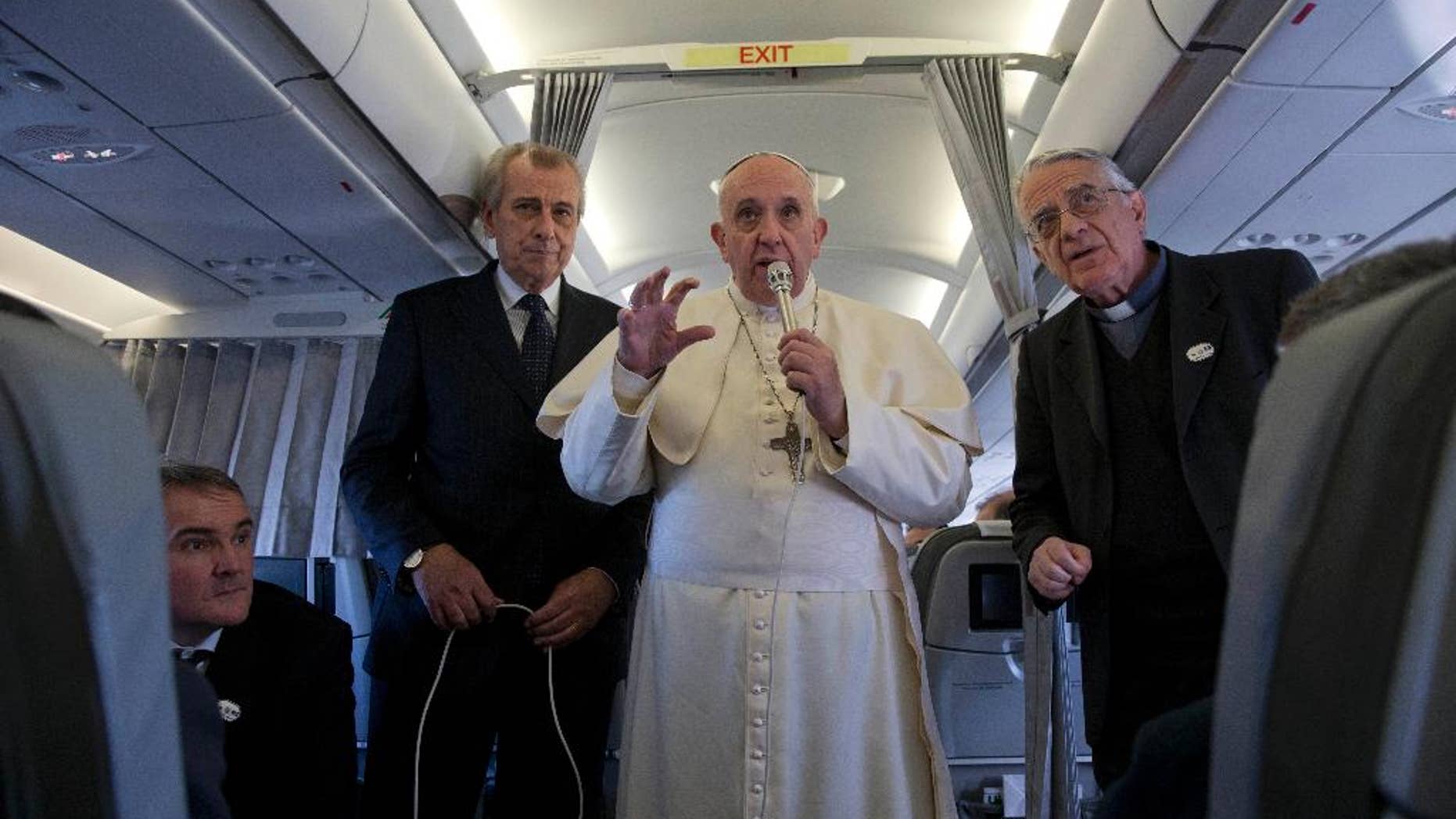 Pope Francis, flanked by Vatican spokesman father Federico Lombardi, first right, talks to journalists during a press conference he held aboard the papal flight on his way back from Strasbourg, eastern France, at the end of a one day visit to the European Parliament and Council, Tuesday, Nov. 25, 2014. Pope Francis has demanded Europe craft a unified and fair immigration policy, saying the thousands of refugees coming ashore need acceptance and assistance, not self-interested policies that risk lives and fuel social conflict. Francis made the comments Tuesday to the European Parliament during a brief visit meant to highlight his vision for Europe a quarter-century after St. John Paul II travelled to Strasbourg to address a continent still divided by the Iron Curtain. (AP Photo/Andrew Medichini)