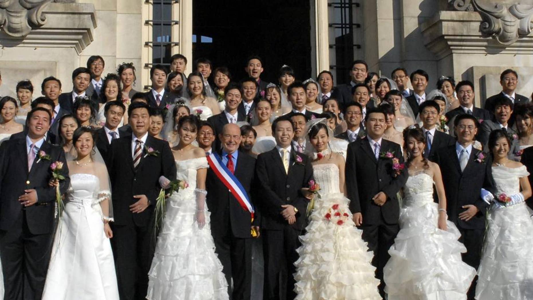 In this photo dated Oct. 2008, Tours mayor, Jean Germain, center, wearing a sash in the colors of the French flag, poses with a group of recently married Chinese couples in front of the city hall in Tours, France. Jean Germain the former mayor of Tours has been found dead in a suspected suicide right as he was to go on trial over suspected kickbacks involving a spate of group weddings of Chinese visitors in the picturesque Loire Valley city. A defense lawyer said a half-dozen people are on trial over alleged kickbacks linked to euro750,000 ($815,000) that the city spent from 2008 to 2011 to lure Asian visitors _ some for weddings presided over by Germain while he was mayor. (AP Photo/Patrice Deschamps, la Nouvelle Republique) FRANCE OUT