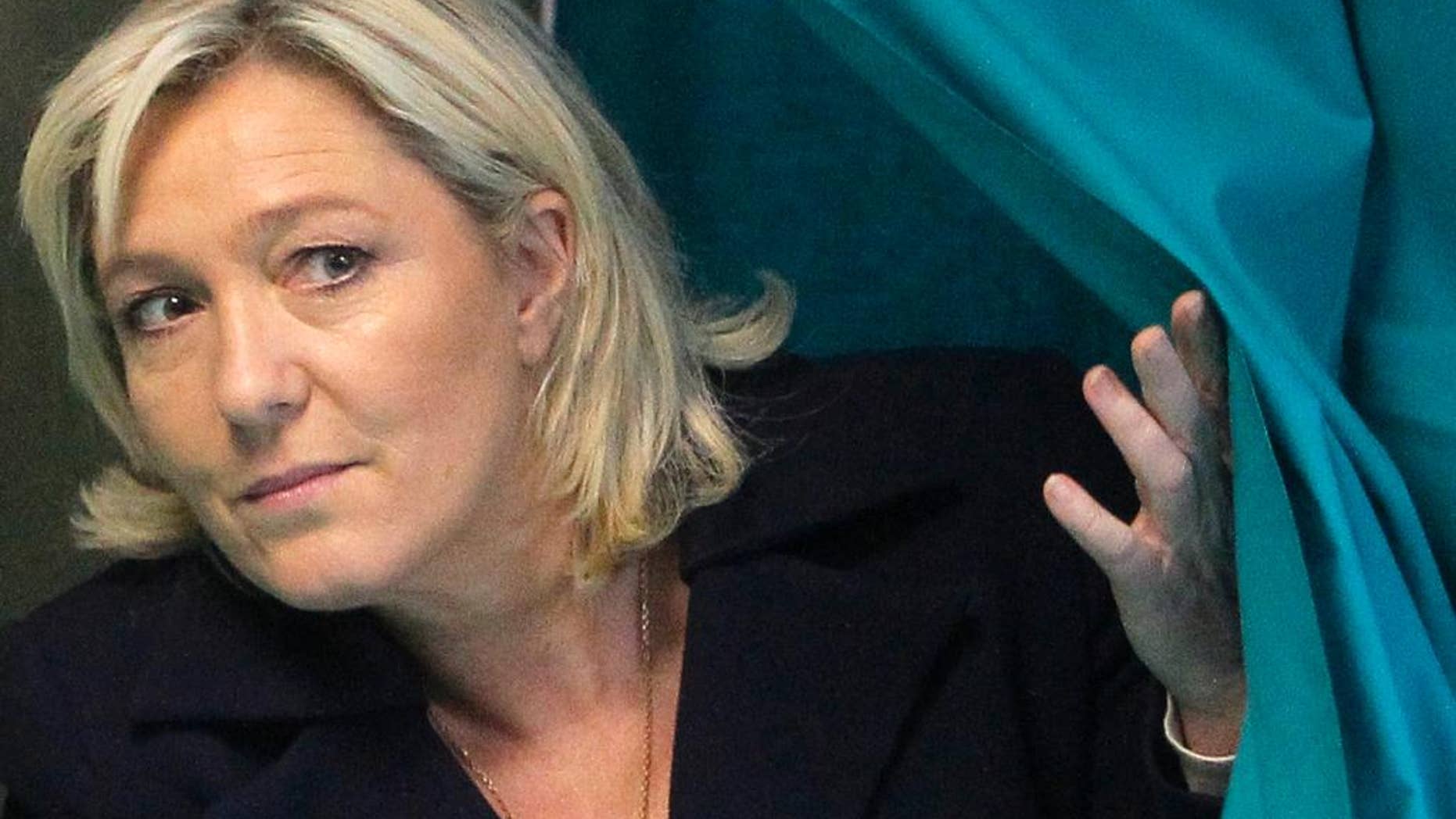 FILE - This Sunday, March 29, 2015 file photo shows French far-right leader and National Front Party, Marine Le Pen, exiting from a polling booth after voting for the second round of local elections in Henin-Beaumont, northern France. A top official in the French far-right National Front party says its leader, Marine Le Pen, will stand trial over comments she made in 2010 comparing Muslim street prayers to an occupation of French territory. Wallerand de Saint Just, Le Pen's former lawyer and a ranking member of the party, confirmed the judicial decision on Tuesday to send Le Pen to trial on charges of inciting racial hatred. (AP Photo/Michel Spingler, File)