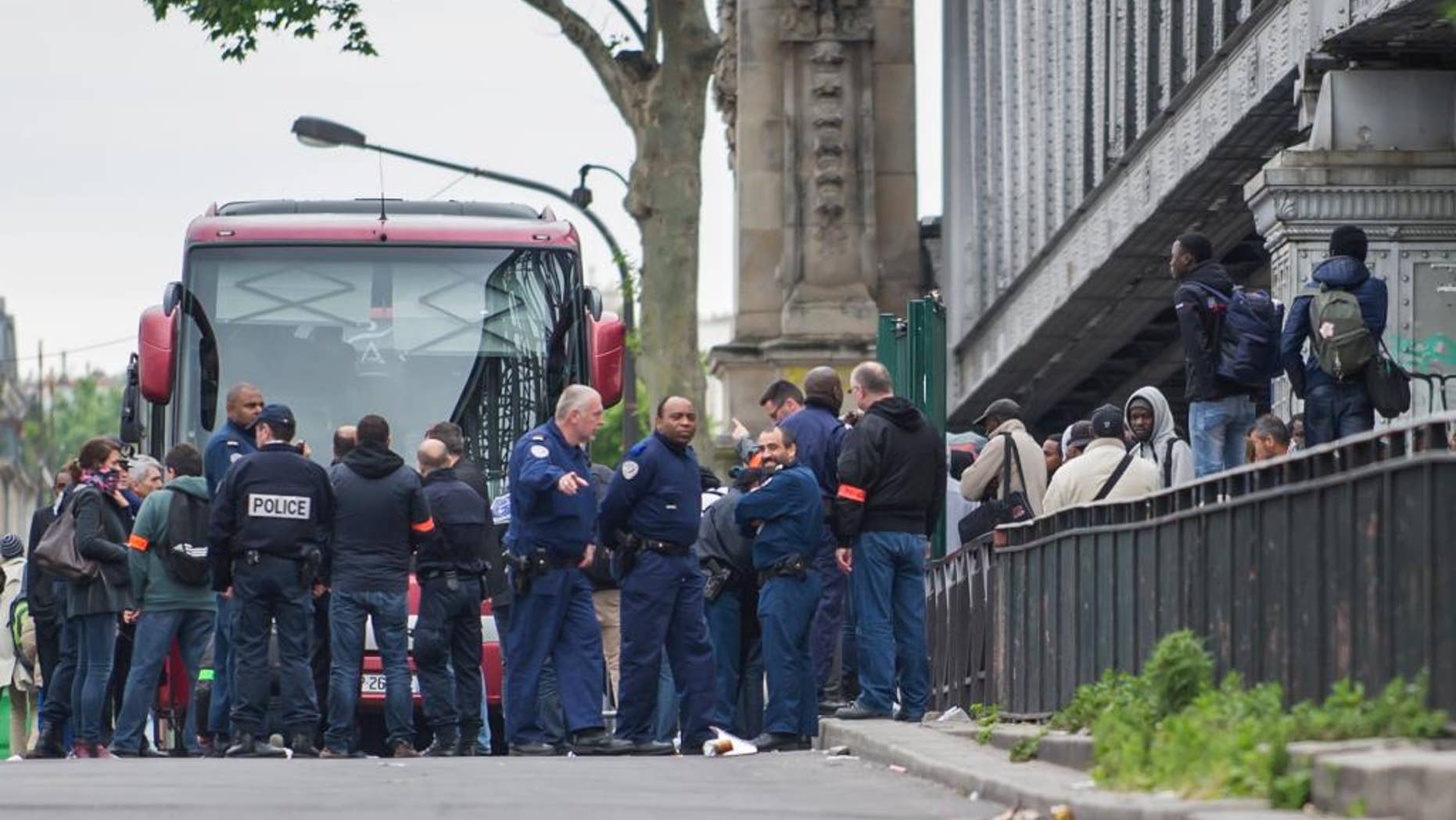 June 2, 2015: Police officers, left, stand near migrants being removed from a tent camp in Paris, France.