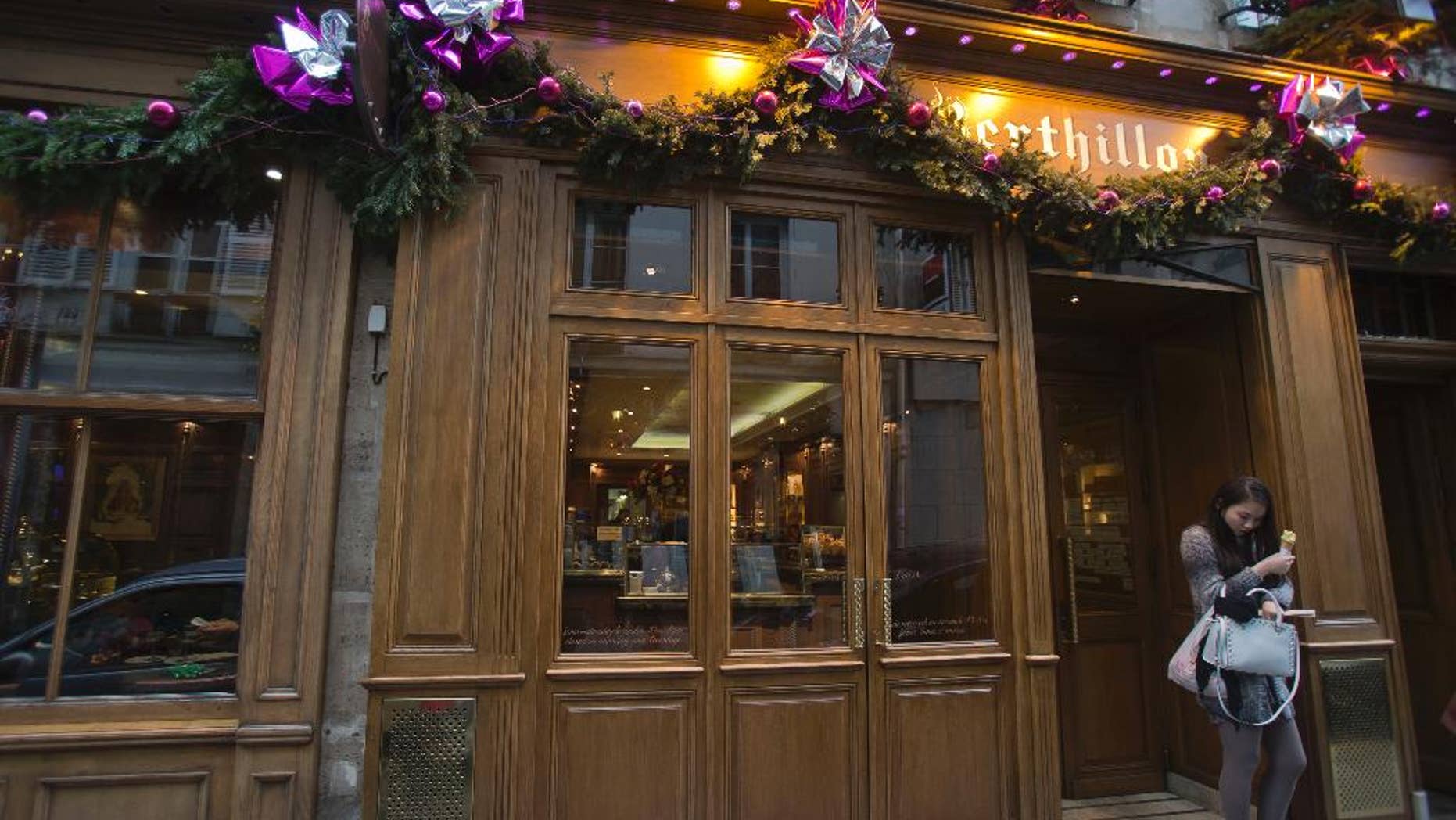 FILE - In this Wednesday, Jan. 8, 2014 file photo, a tourist holds an ice cream cone as she walks out of the Berthillon ice cream parlor on the Ile Saint-Louis in Paris. Raymond Berthillon, the founder of the celebrated Paris ice cream parlor that bears his name, has died at age 90. The company, which closes for the month of August, announced the Saturday, Aug. 9, 2014 death of the patriarch on its web site. (AP Photo/Michel Euler, File)