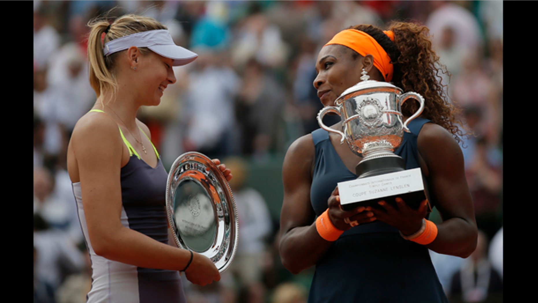 June 8, 2013: Serena Williams of the U.S., right, holds the trophy after defeating Russia's Maria Sharapova, left, in two sets 6-4, 6-4, in the women's final of the French Open tennis tournament, at Roland Garros stadium in Paris.