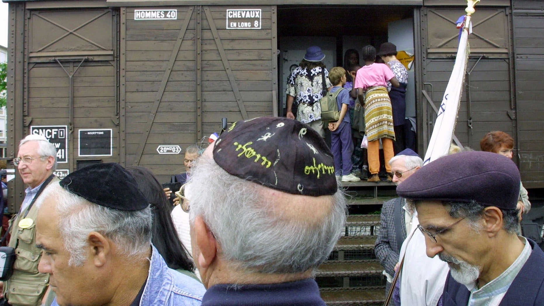 Aug. 20, 2001 - FILE photo of French Holocaust survivors gathering at the site of the former Drancy detention camp, north of Paris. From Aug. 20, 1941 until the end of World War II, more than 70,000 Jewish men, women and children passed through Drancy on their way to Nazi extermination camps, particularly Auschwitz. The wagon is part of the memorial site. Hundreds of Americans and others deported by France's state rail company SNCF during the Nazi occupation will be entitled to compensation under a new U.S.-French agreement.