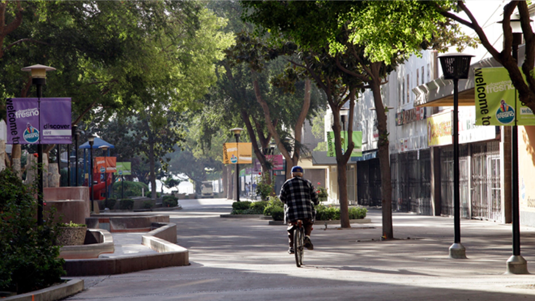 In this photo taken on Friday Sept. 20, 2013 in Fresno, Calif., a man rides his bike on the Fulton Mall, a six-block pedestrian mall once touted as a national model for pedestrian-friendly downtowns. While many U.S. cities are converting urban cores into walkable oases, Fresno leaders want to convert the struggling pedestrian mall back into a street. (AP Photo/Gosia Wozniacka)