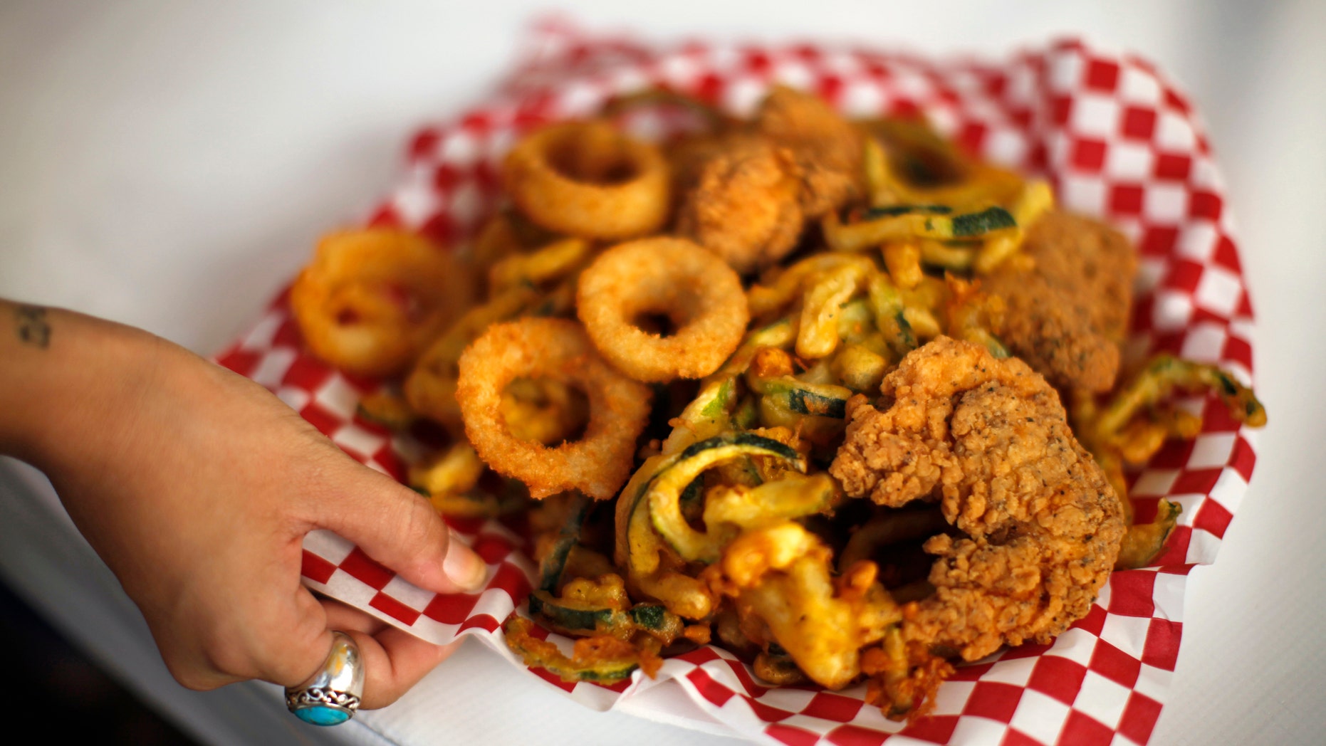 A woman holds a plate of fried food at the Los Angeles County Fair in Pomona, California September 5, 2012. The nation's largest county fair, running from August 31 to September 30, is celebrating its 90th anniversary. REUTERS/Lucy Nicholson (UNITED STATES - Tags: FOOD SOCIETY ANNIVERSARY) - RTR37K1S