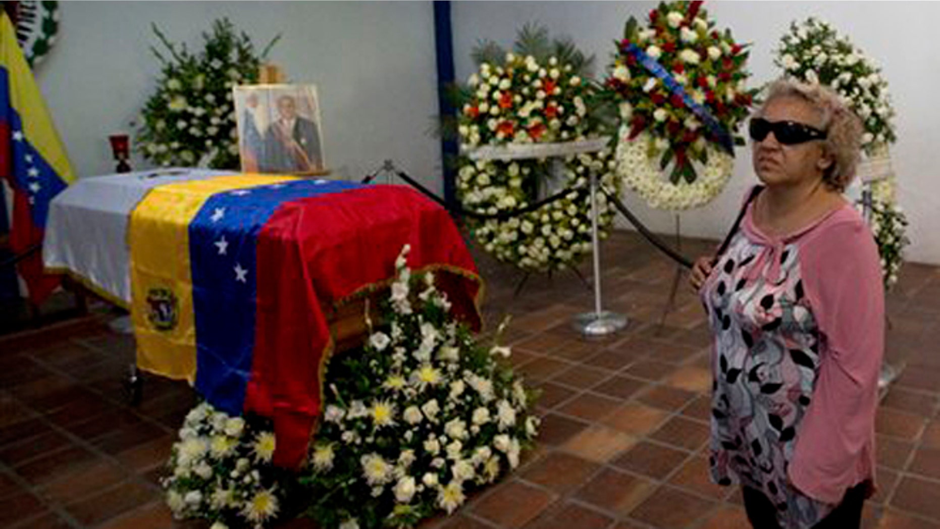 A woman stands near the coffin that contain the remains of Venezuela's late President Jaime Lusinchi during a memorial service in Caracas, Venezuela, Thursday, May 22, 2014. The former president, who struggled to tame an economic crisis sparked by plunging oil prices in the late 1980s and then saw his reputation tarnished by allegations of corruption after leaving office, died Wednesday, May 21, 2014. He was 89. (AP Photo/Fernando Llano)