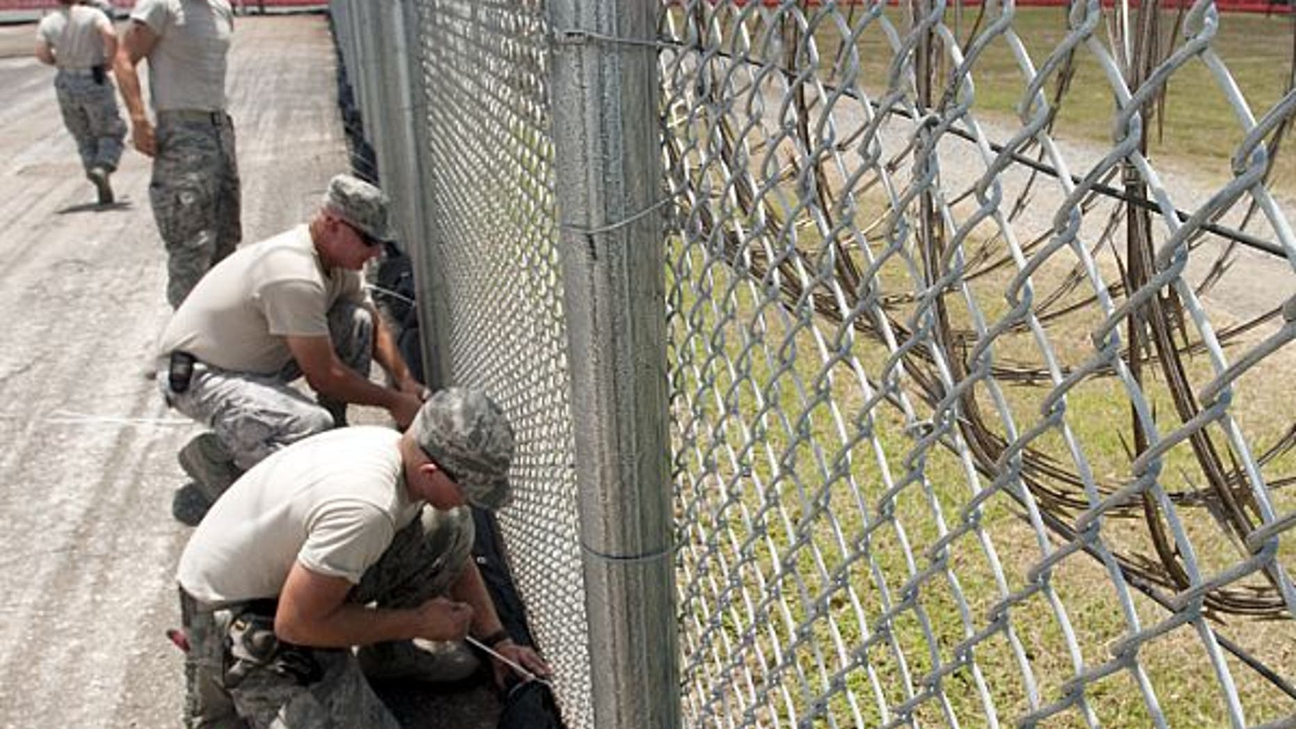 120823-N-RG482-062GUANTANAMO BAY, Cuba (Aug. 23, 2012) Airmen from the 474th Expeditionary Civil Engineering Squadron/Base Emergency Engineering Force tie down security netting near the Office of Military Commissions facilities at Naval Base Guantanamo Bay in preparation for Tropical Strorm Isaac. The storm is expected to make landfall on Saturday.(U.S. Navy photo by Mass Communication Specialist 2nd Class Kyle Steckler/Released)