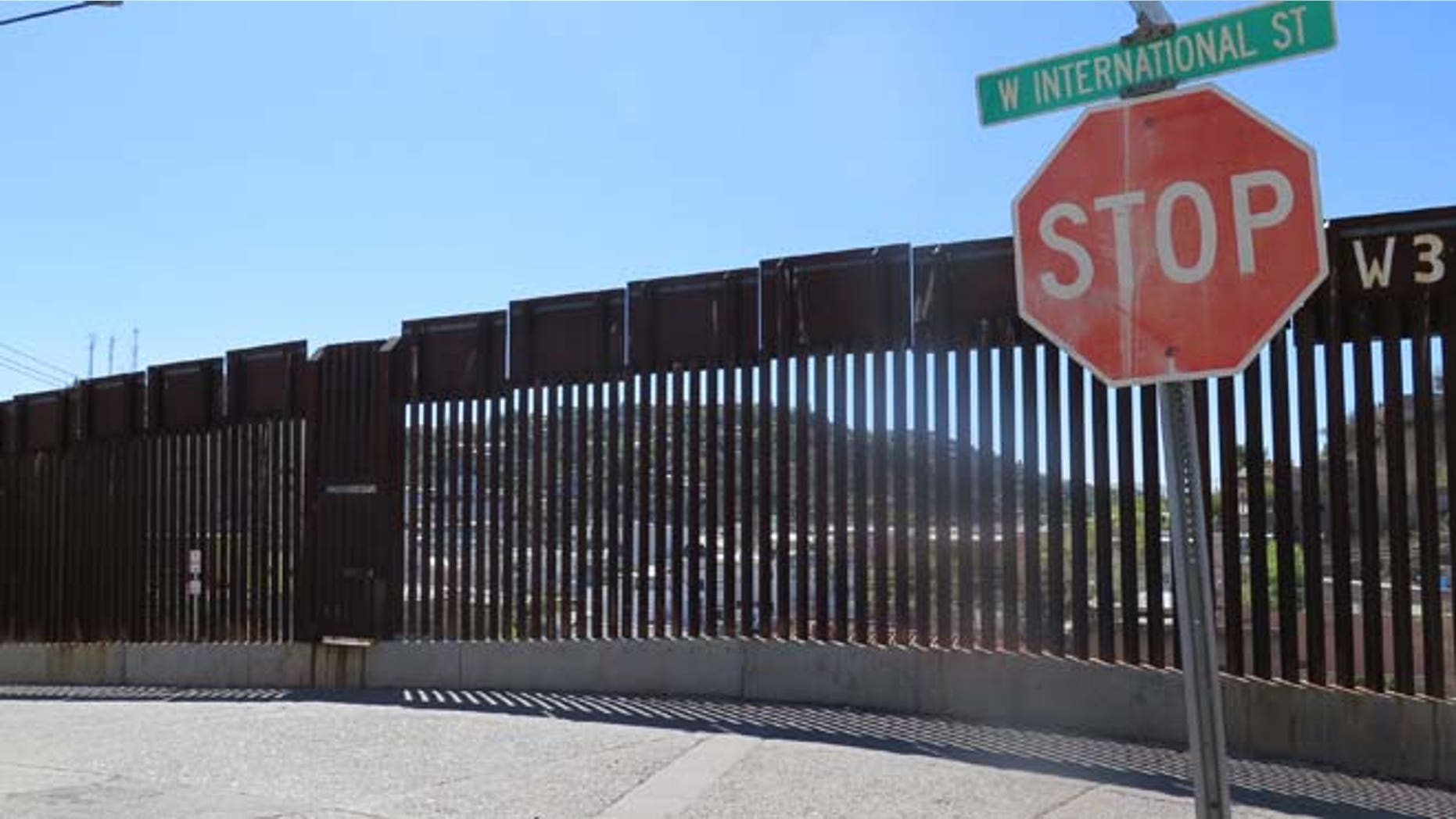 A stop sign in front of the international border fence in Nogales, Ariz.