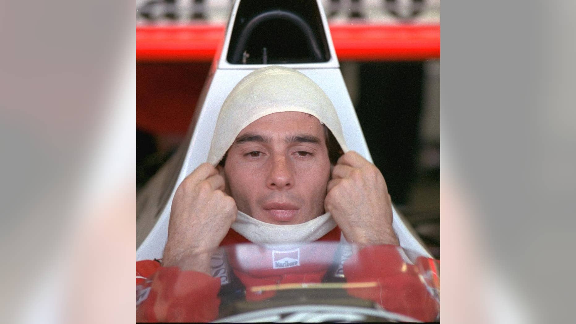 FILE - In this November 4, 1989, file photo, Brazilian driver Ayrton Senna, in a McLaren Honda, pulls on a fire resistant mask before going out to practice for the Australian Grand Prix. Senna won three Formula One titles — in 1988, 1990 and '91 — all with McLaren. He moved to the Williams team for his tragic 1994 season. Despite his career being cut short when he was 34, his 41 wins stand third all-time behind Michael Schumacher's 91 and rival Alain Prost's 51. He died at the 1994 San Marino Grand Prix. (AP Photo/Stephan Holland, File)