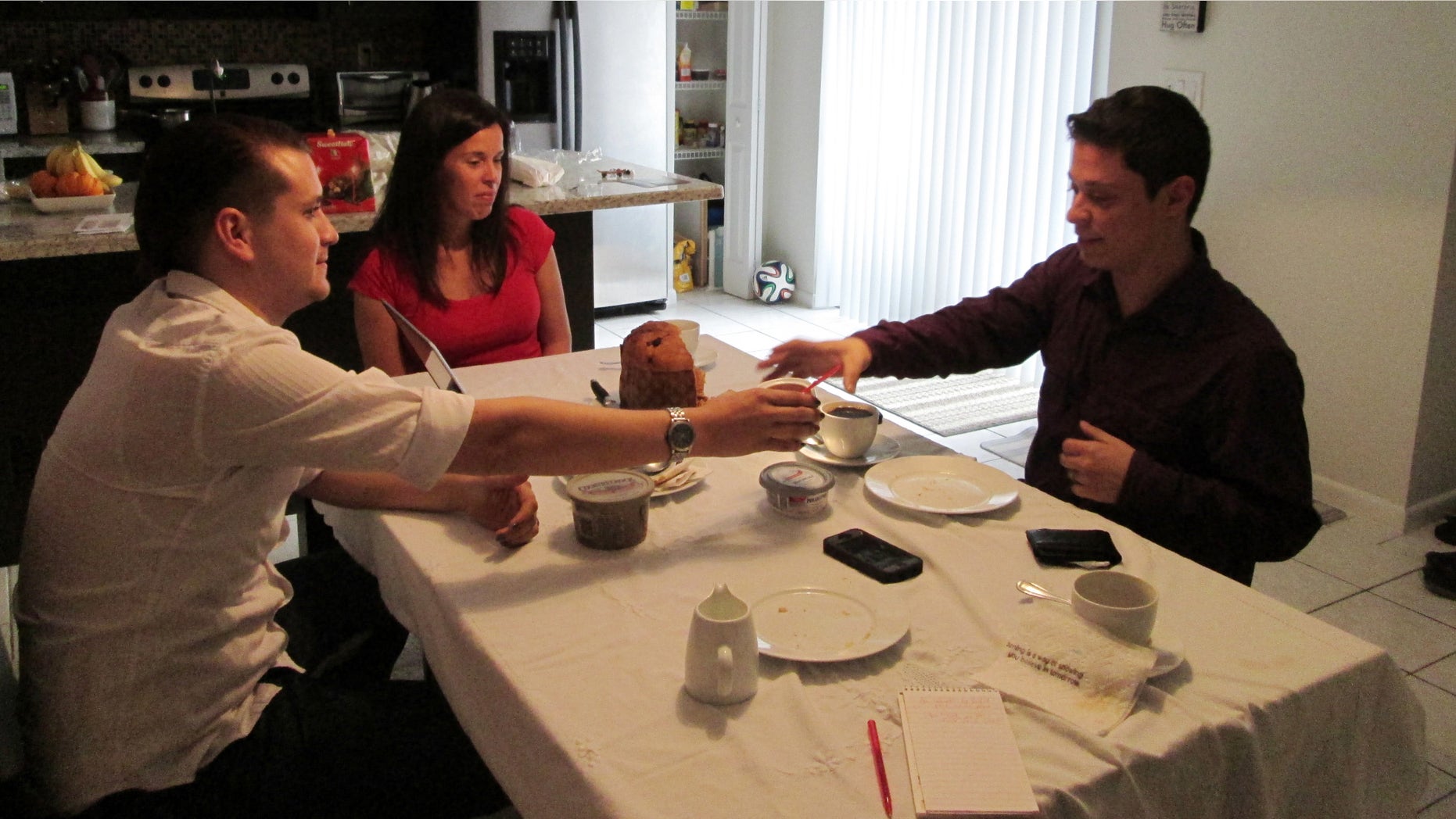 In this Tuesday, Dec. 23, 2014 photo, Isabel Rodriguez, left, hands coffee to his husband, Felipe Sousa-Rodriguez, right, at the Davie, Fla. home of Felipeâs sister. The two are longtime immigrant and LGBTQ activists who walked from Miami to Washington, in 2010, to call attention to the struggles of youth living in the United States illegally. (AP Photo/Laura Wides-Munoz)