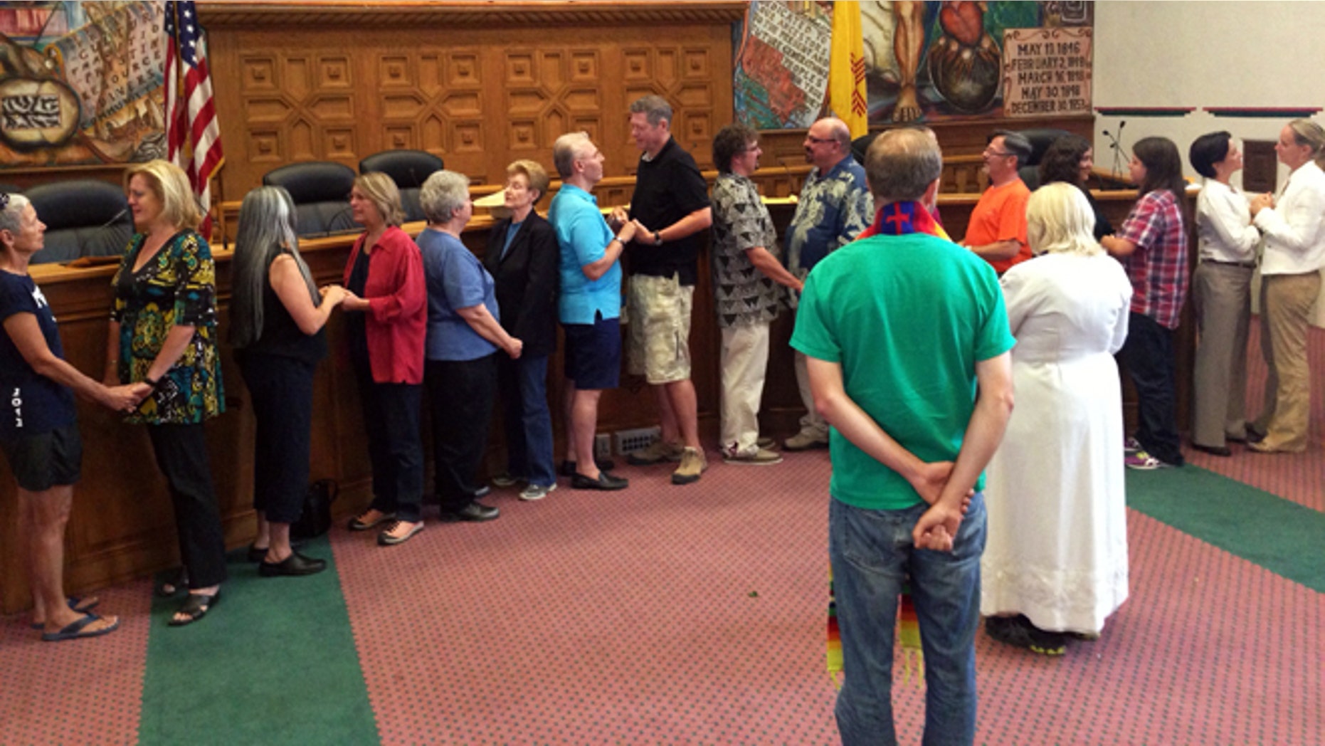Nine same-sex couples take their wedding vows in the Santa Fe County Commission's chambers after receiving marriage licenses in Santa Fe, N.M., on Friday, Aug. 23. The Rev. Talitha Arnold, in white in foreground, of the United Church of Santa Fe officiated the ceremony. (AP Photo/Barry Massey)