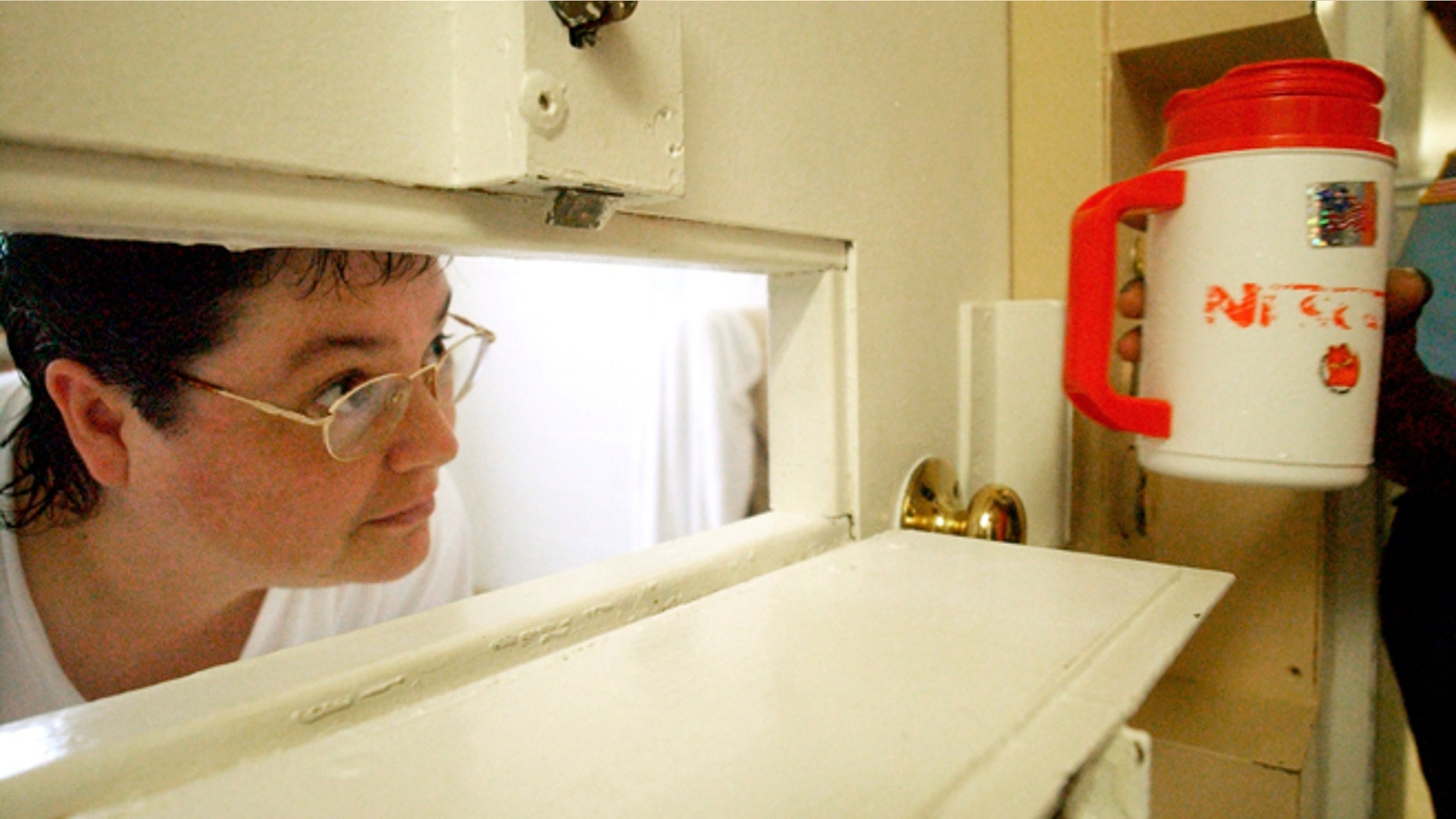 July 6, 2004: In this file photo, Kelly Gissendaner, the only woman on Georgia's death row, peers through the slot in her cell door as a guard brings her a cup of ice at Metro State Prison in Atlanta. (AP/Atlanta Journal-Constitution, Bita Honarvar, File)