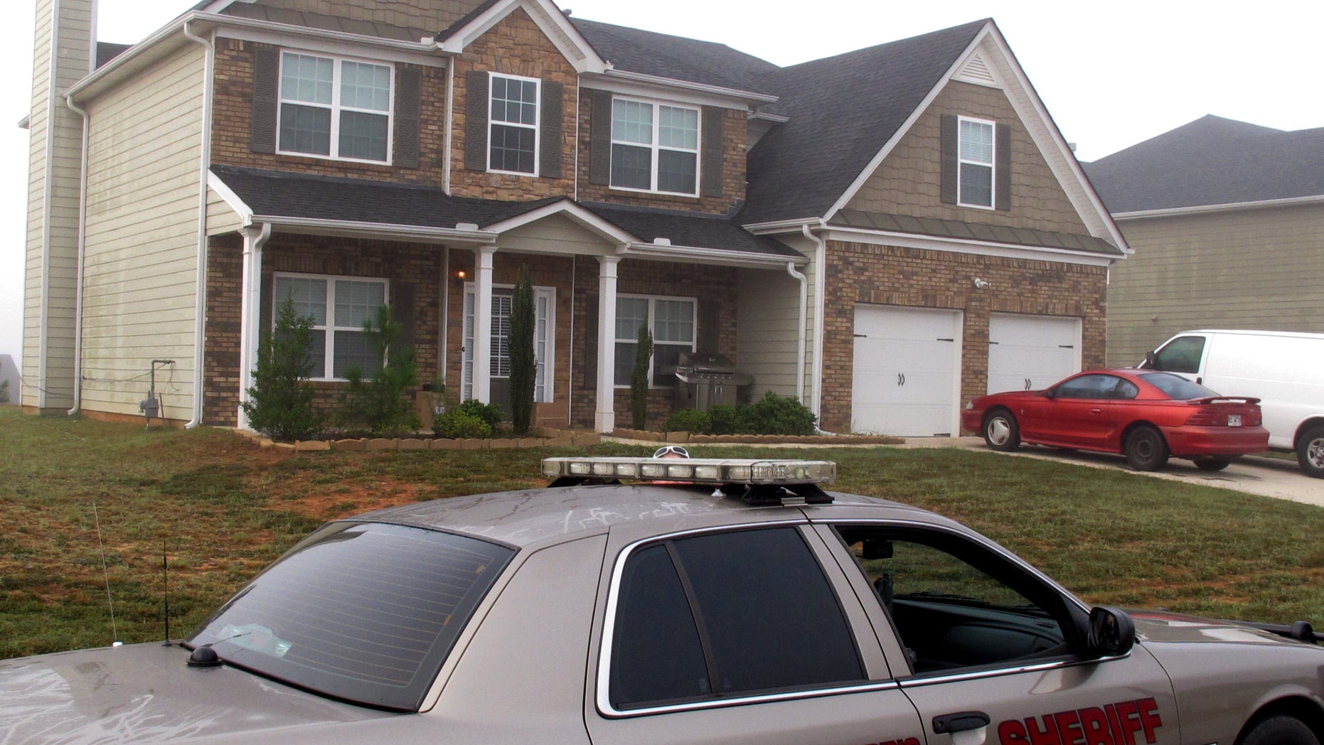 Friday, Sept. 21, 2012 - A Paulding County sheriff's deputy sits outside the suburban home in Dallas, Georgia, near Atlanta, where authorities say Paul and Sheila Comer kept their 18-year-old son in a bedroom for about two years.