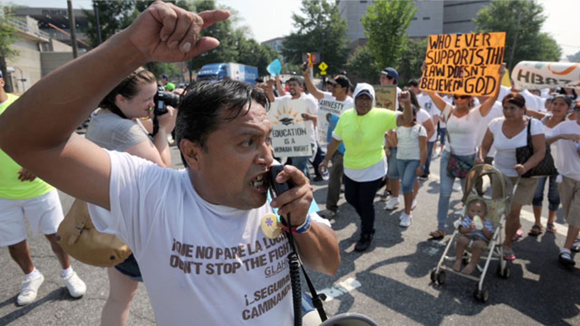 Tomas Martinez shouts slogans while leading thousands of people in a march through downtown Atlanta in protest against Georgia's strict new immigration law on Saturday, July 2, 2011 in Atlanta.