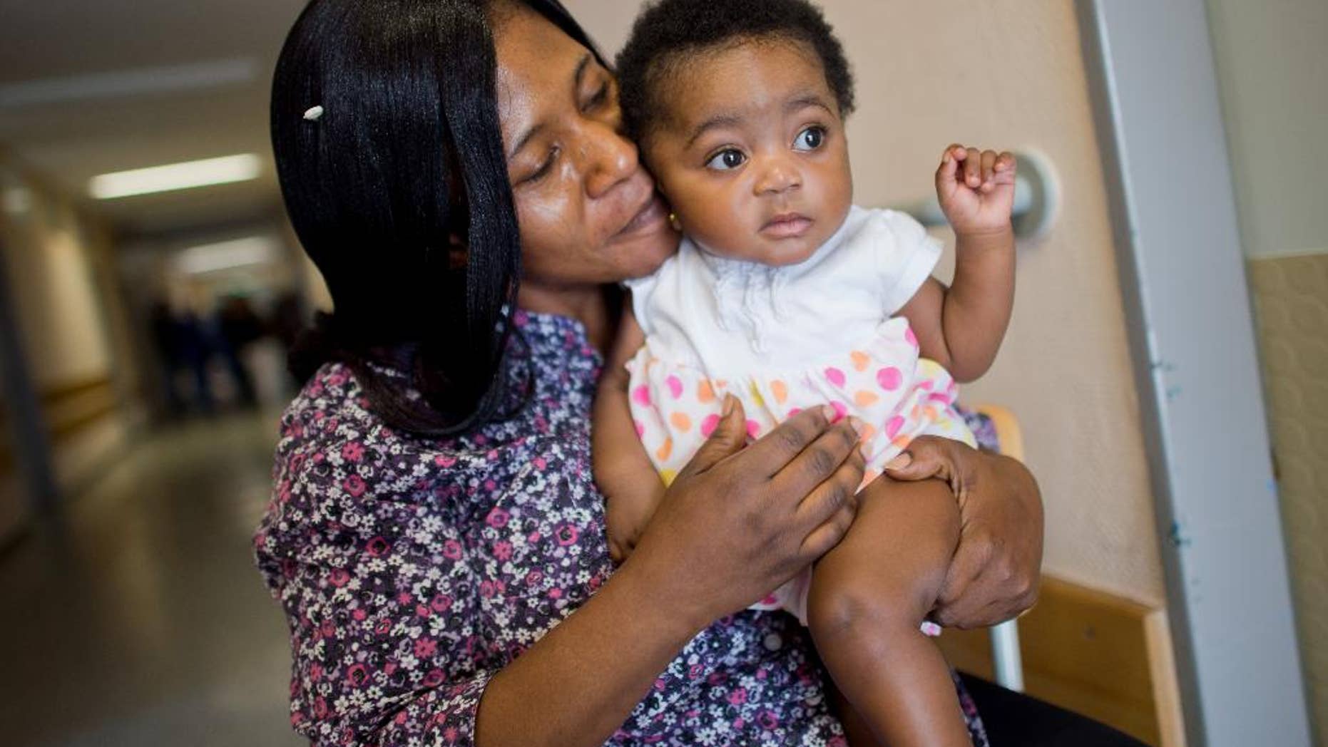 Six-month-old Angela Merkel Ade sits on the arm of her mother Ophelya Ade in a refugee shelter in a former hospital in Hannover, northern Germany. Ophelya Ade _ an asylum seeker from Ghana _named her daughter after the German chancellor. (Julian Stratenschulte/dpa via AP)